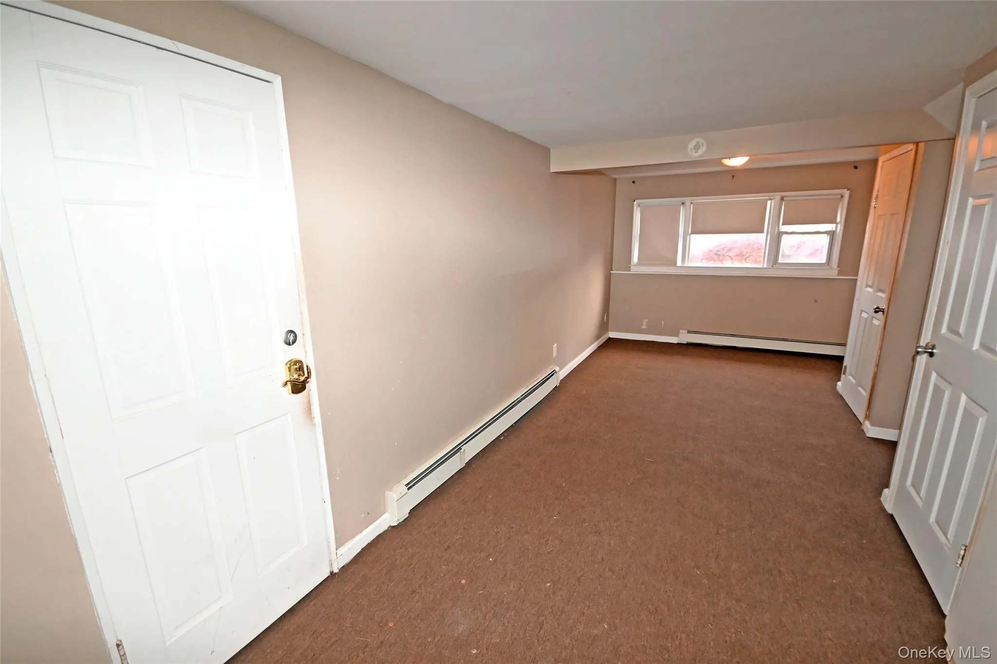 Corridor featuring a baseboard heating unit and carpet floors Corridor featuring a baseboard heating unit and carpet floors