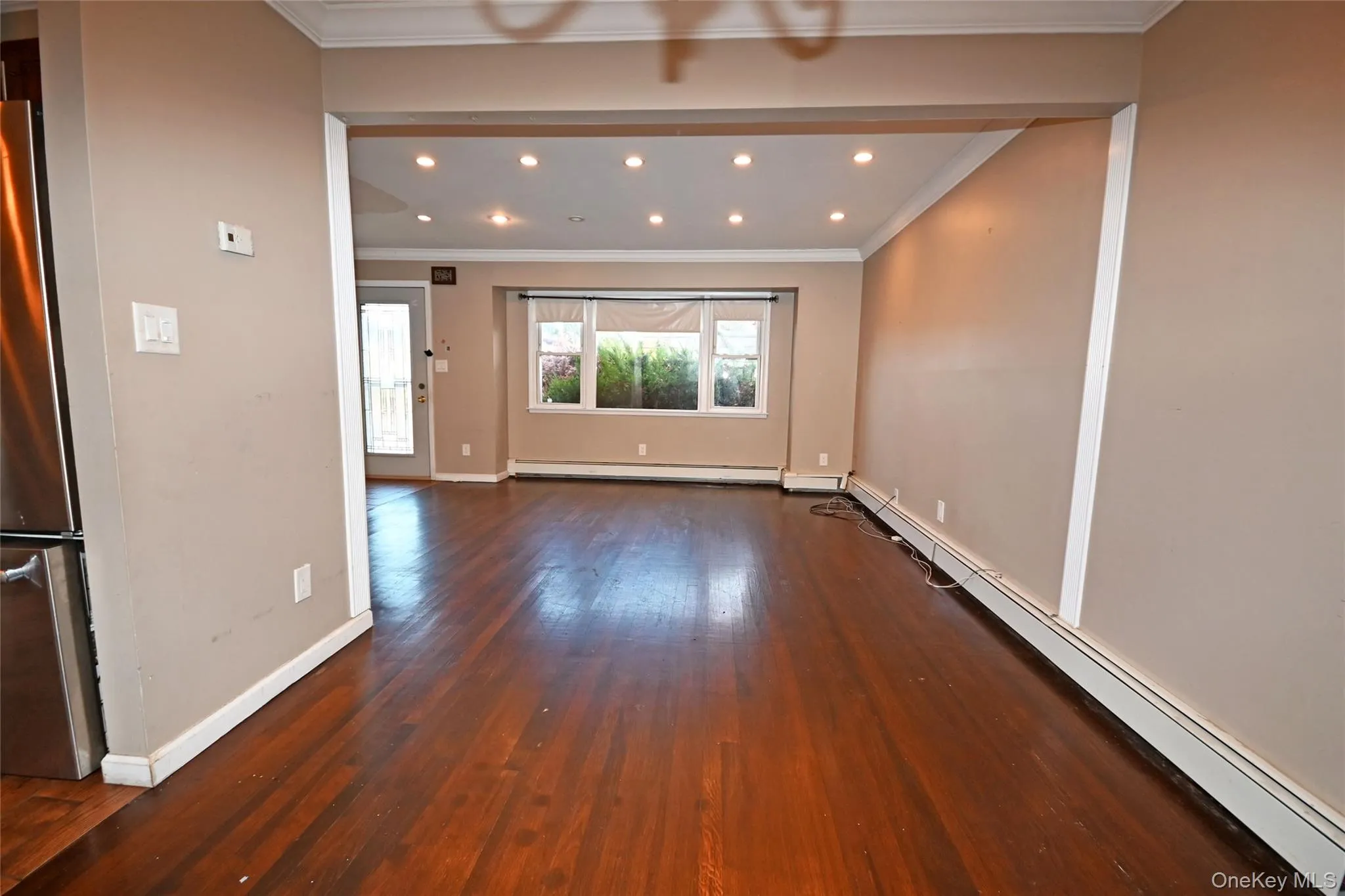 Unfurnished room featuring a baseboard heating unit, crown molding, dark wood finished floors, and recessed lighting Unfurnished room featuring a baseboard heating unit, crown molding, dark wood finished floors, and recessed lighting