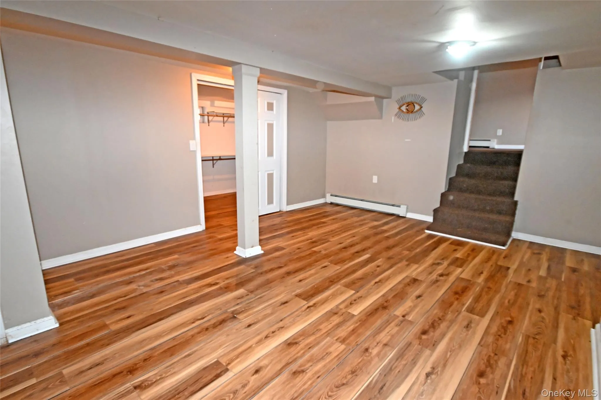 Finished basement with a baseboard radiator, light wood finished floors, and stairs Finished basement with a baseboard radiator, light wood finished floors, and stairs