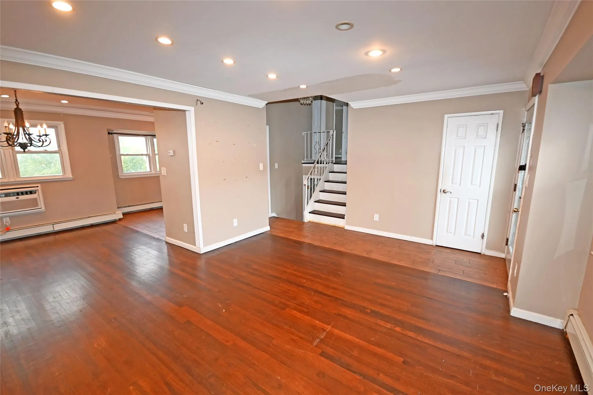 Unfurnished room with ornamental molding, a wall mounted AC, recessed lighting, dark wood-style floors, and baseboard heating Unfurnished room with ornamental molding, a wall mounted AC, recessed lighting, dark wood-style floors, and baseboard heating