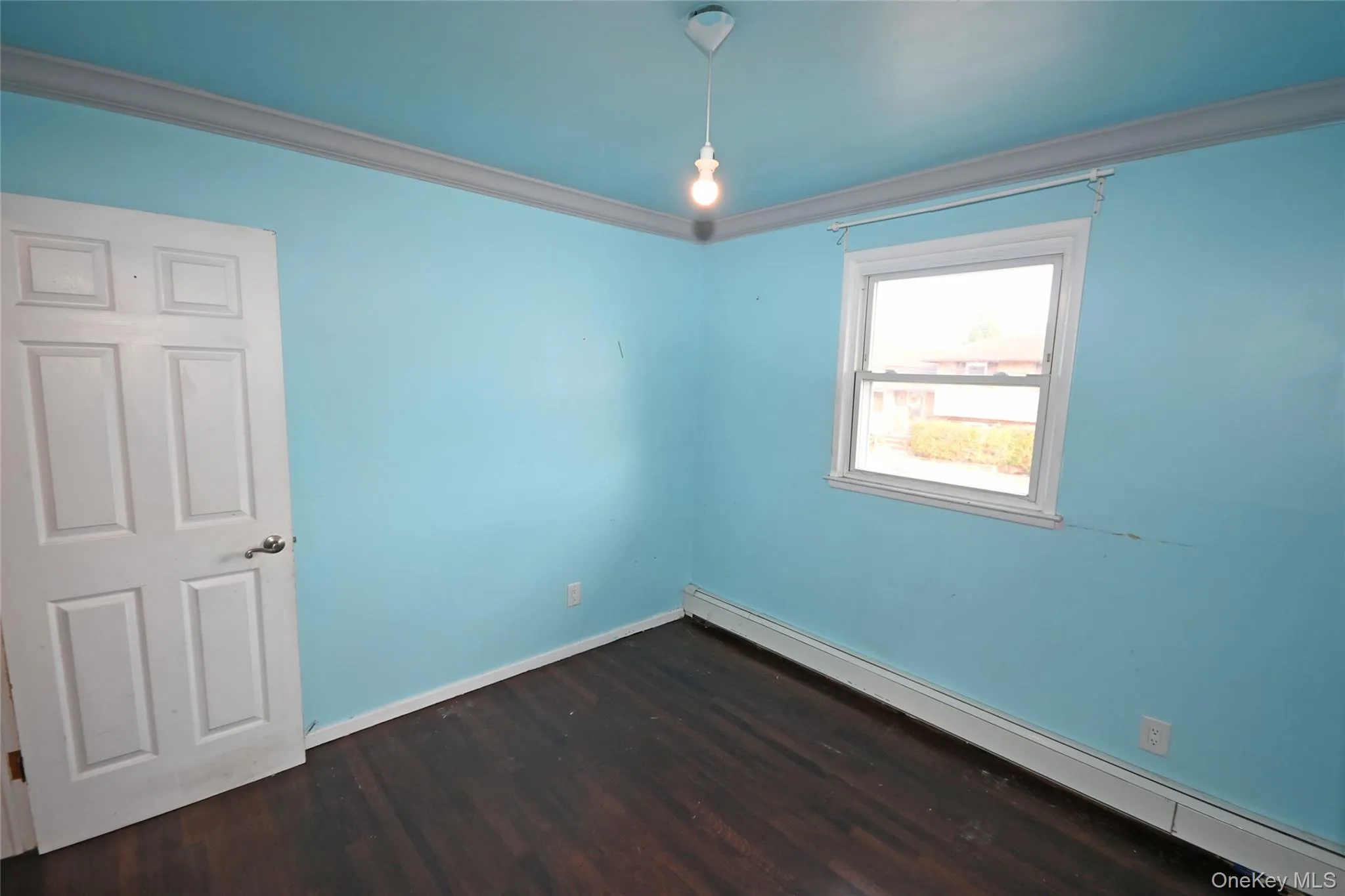 Empty room featuring a baseboard radiator, crown molding, and dark wood-style flooring Empty room featuring a baseboard radiator, crown molding, and dark wood-style flooring
