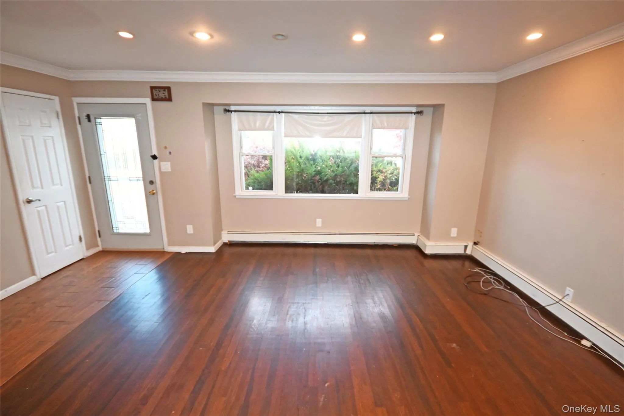 Spare room featuring crown molding, dark wood-style flooring, recessed lighting, and a baseboard heating unit Spare room featuring crown molding, dark wood-style flooring, recessed lighting, and a baseboard heating unit