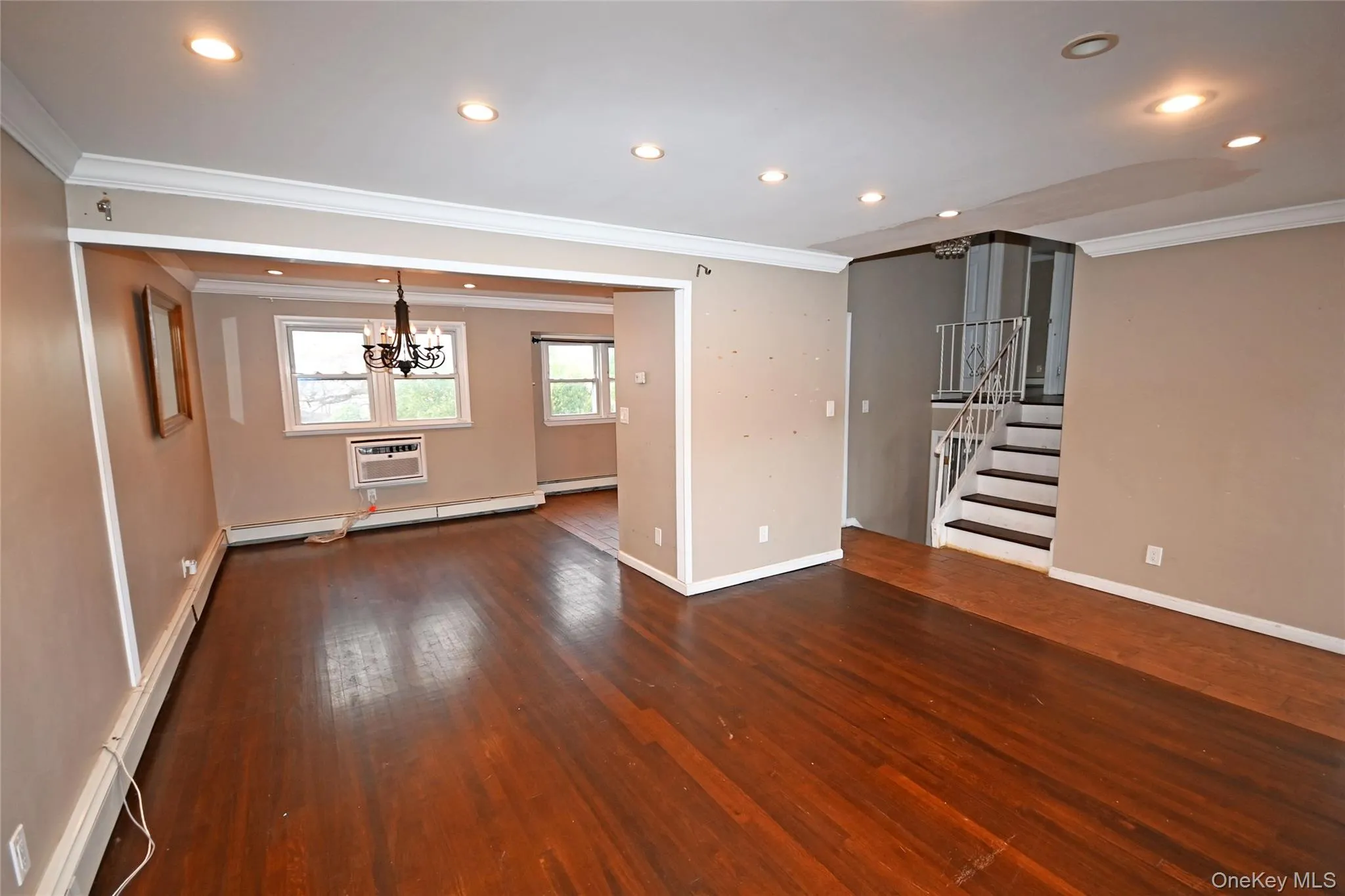 Unfurnished living room with ornamental molding, recessed lighting, stairway, wood-type flooring, and a wall unit AC Unfurnished living room with ornamental molding, recessed lighting, stairway, wood-type flooring, and a wall unit AC