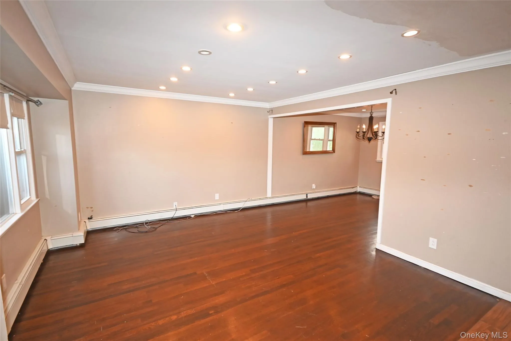 Spare room featuring ornamental molding, recessed lighting, dark wood-type flooring, a chandelier, and baseboard heating Spare room featuring ornamental molding, recessed lighting, dark wood-type flooring, a chandelier, and baseboard heating