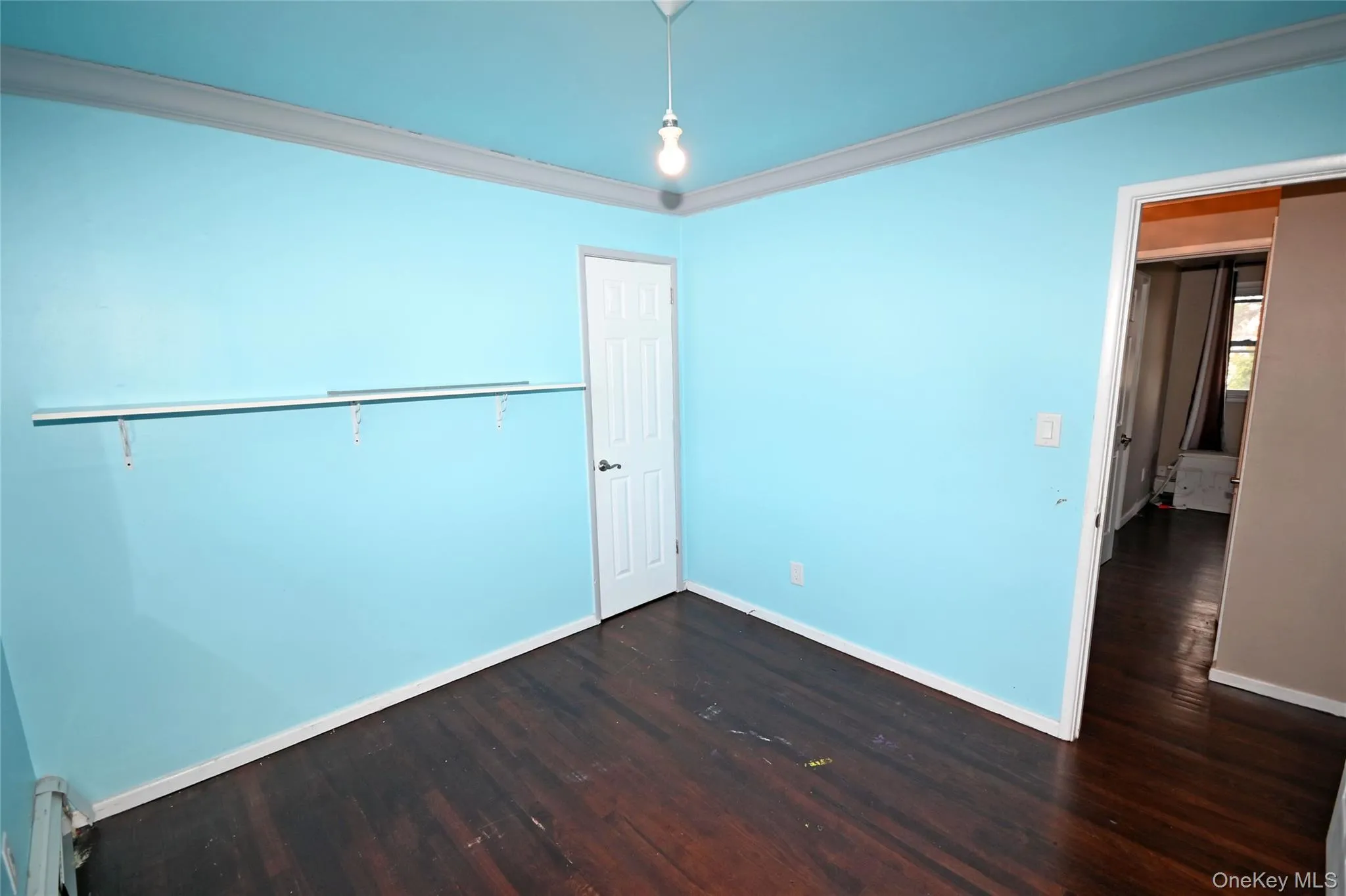 Unfurnished bedroom featuring crown molding and dark wood finished floors Unfurnished bedroom featuring crown molding and dark wood finished floors