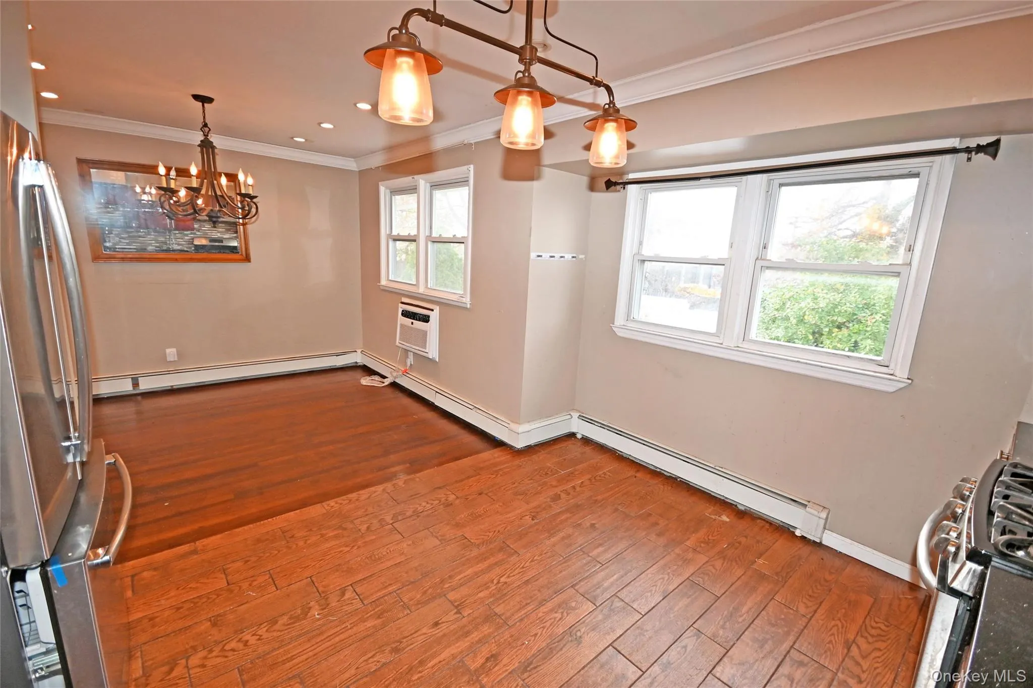 Unfurnished dining area featuring a chandelier, crown molding, hardwood / wood-style floors, baseboard heating, and recessed lighting Unfurnished dining area featuring a chandelier, crown molding, hardwood / wood-style floors, baseboard heating, and recessed lighting