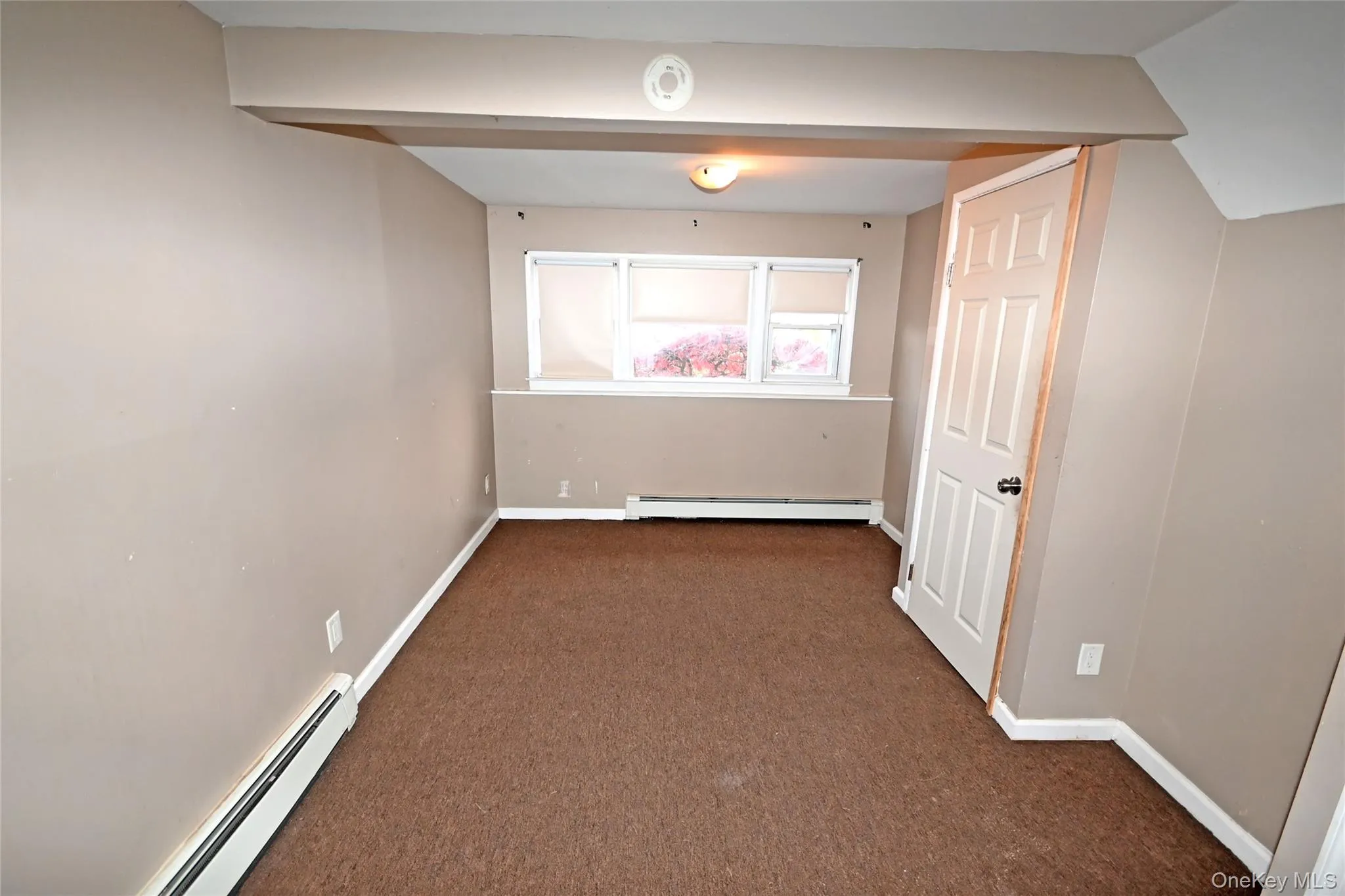 Empty room featuring a baseboard heating unit and carpet Empty room featuring a baseboard heating unit and carpet
