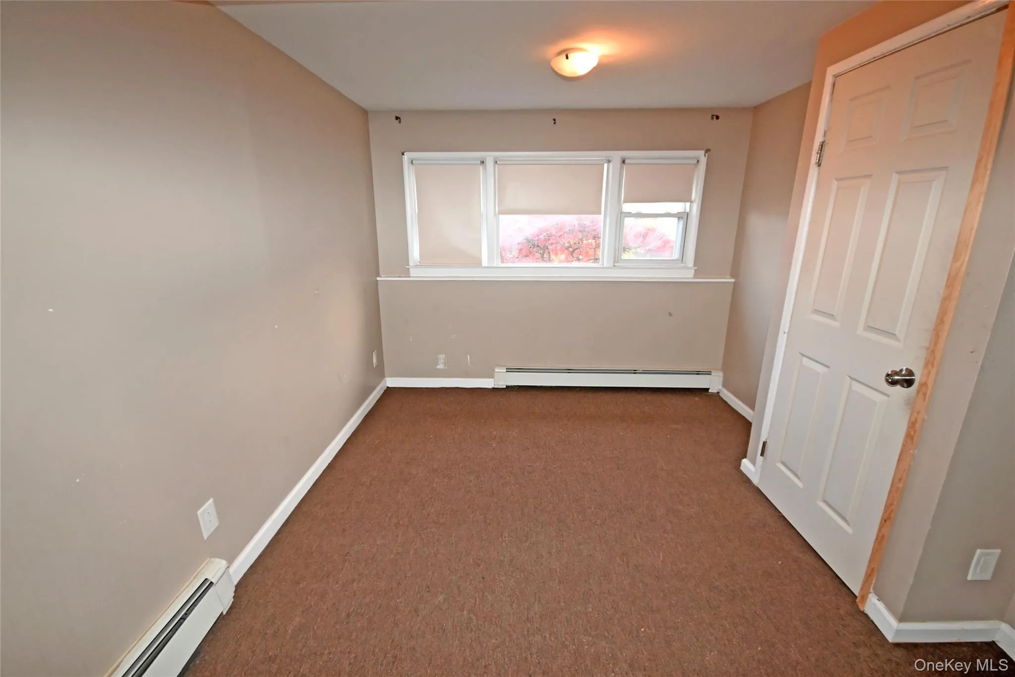 Unfurnished bedroom with baseboard heating and carpet Unfurnished bedroom with baseboard heating and carpet