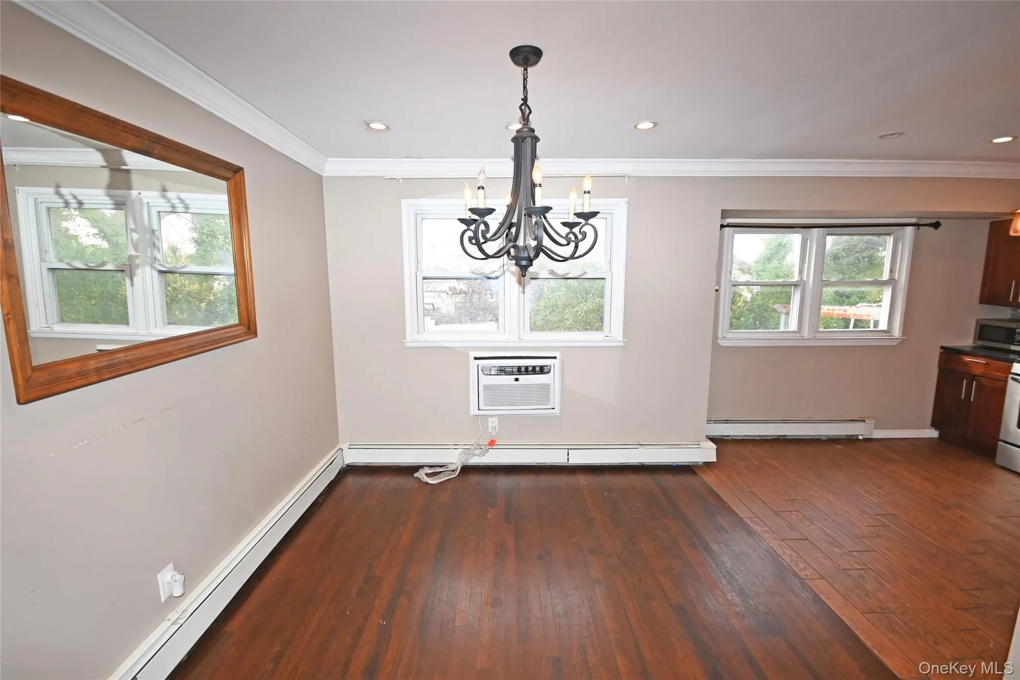 Unfurnished dining area with dark wood-type flooring, baseboard heating, crown molding, a chandelier, and recessed lighting Unfurnished dining area with dark wood-type flooring, baseboard heating, crown molding, a chandelier, and recessed lighting
