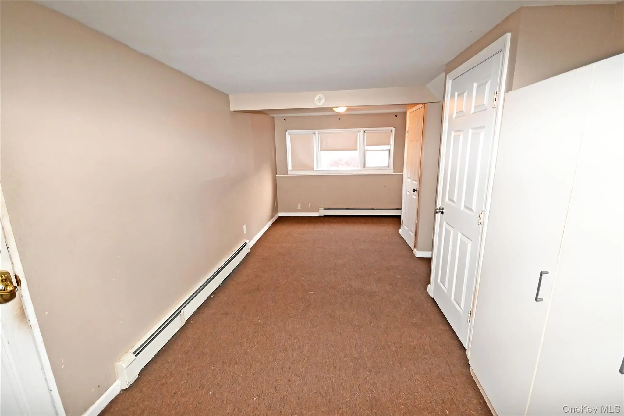 Hall with a baseboard heating unit and carpet flooring Hall with a baseboard heating unit and carpet flooring