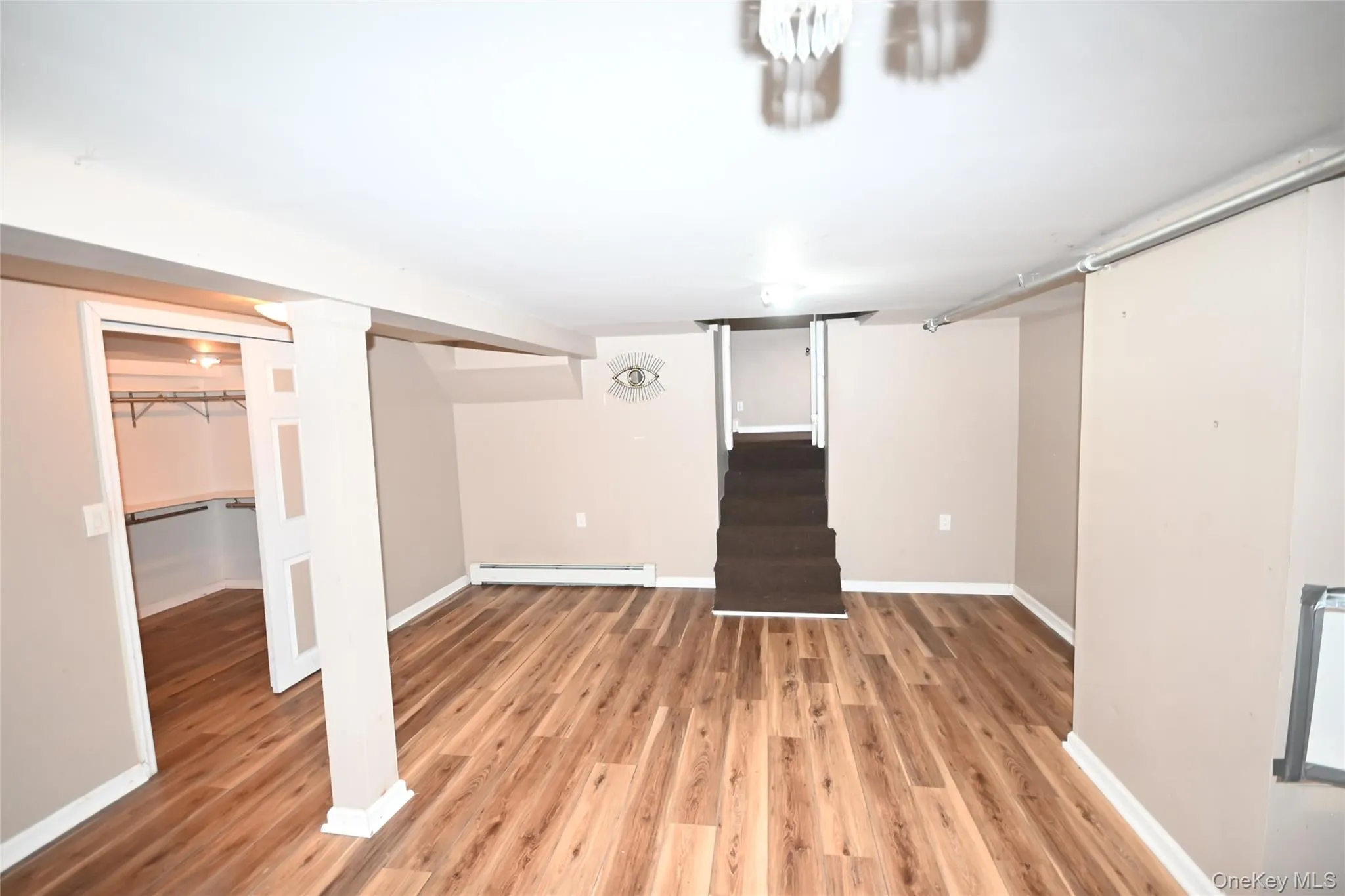 Finished basement featuring stairway, light wood finished floors, and baseboard heating Finished basement featuring stairway, light wood finished floors, and baseboard heating