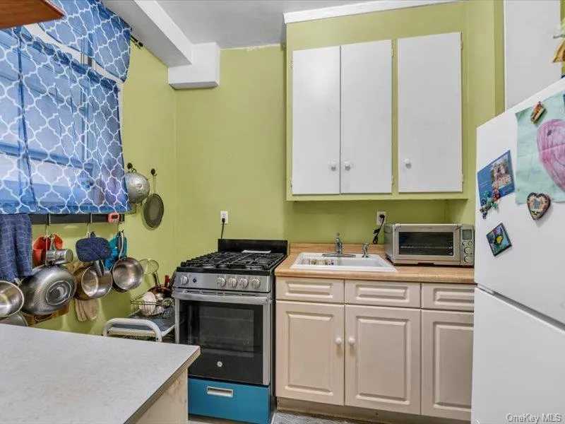 Kitchen featuring stainless steel range with gas cooktop, freestanding refrigerator, white cabinets, and light countertops Kitchen featuring stainless steel range with gas cooktop, freestanding refrigerator, white cabinets, and light countertops