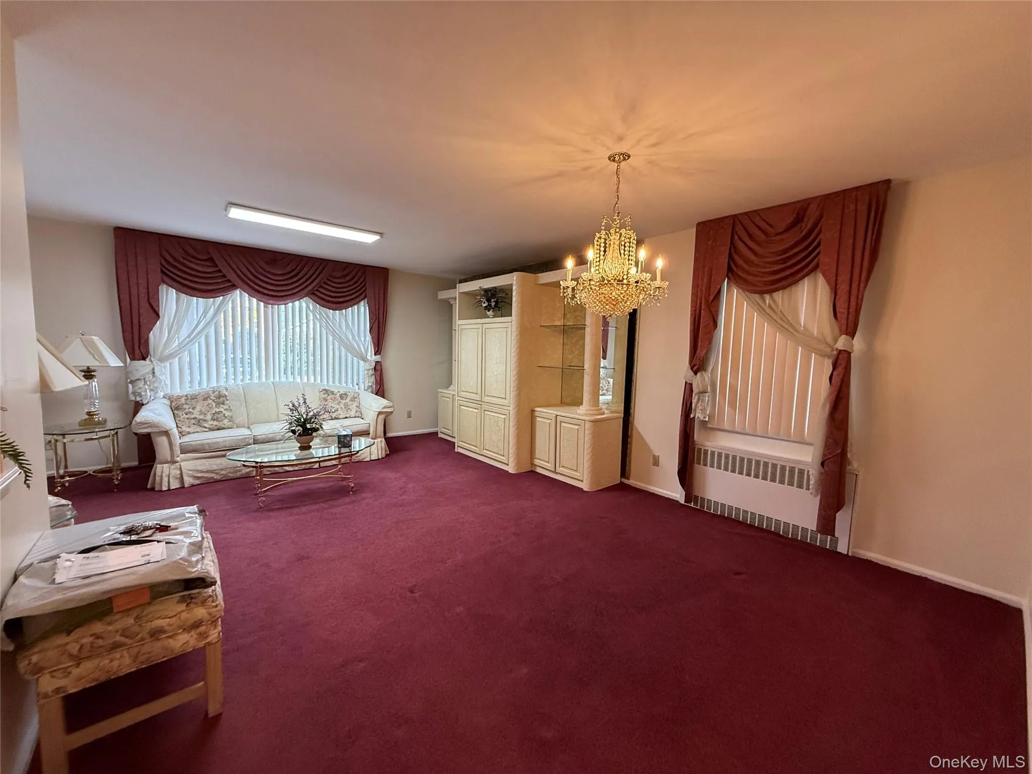 Living area with a chandelier, radiator heating unit, and carpet Living area with a chandelier, radiator heating unit, and carpet