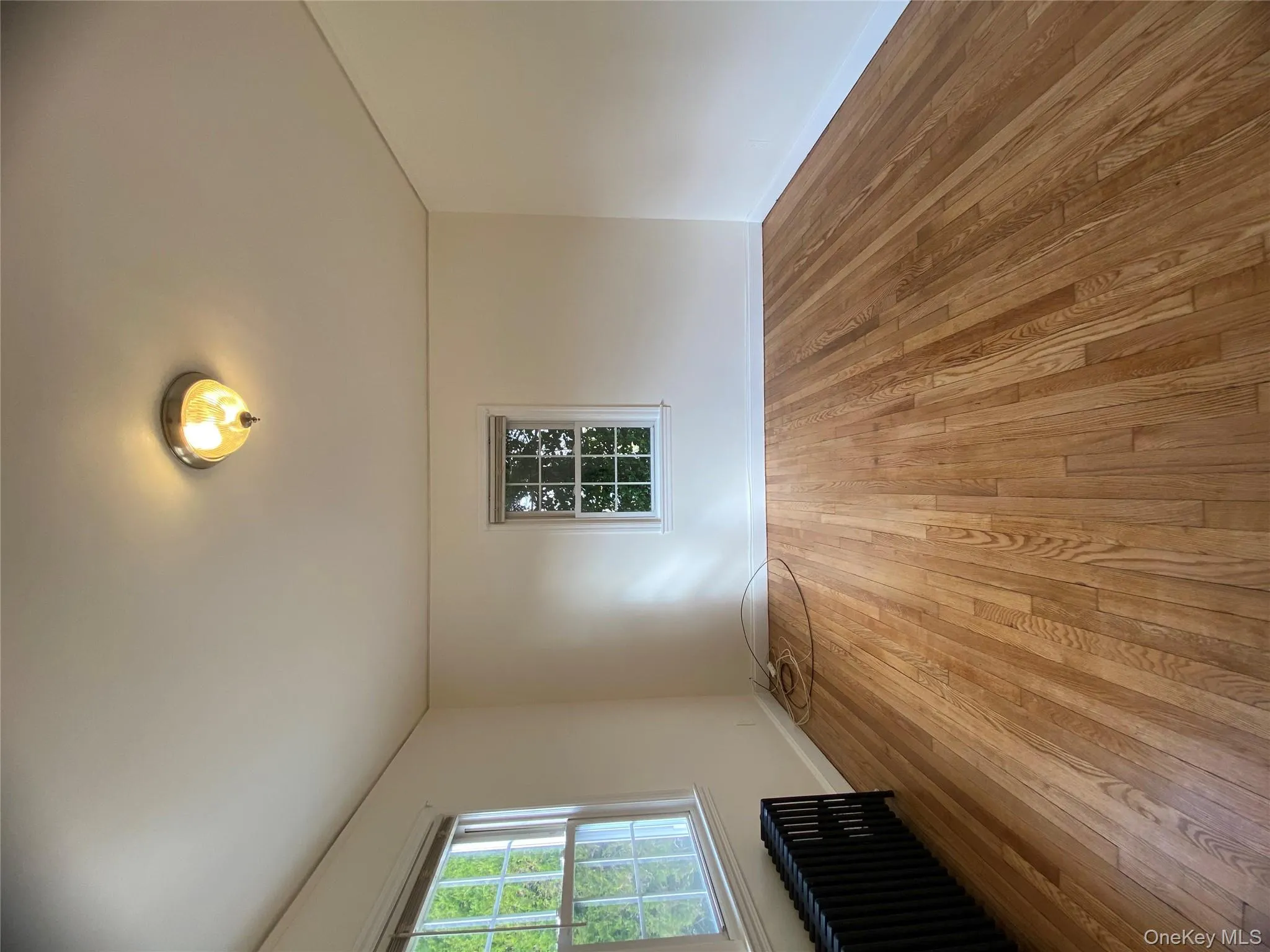 Empty room featuring radiator heating unit, wood-type flooring, and healthy amount of natural light Empty room featuring radiator heating unit, wood-type flooring, and healthy amount of natural light