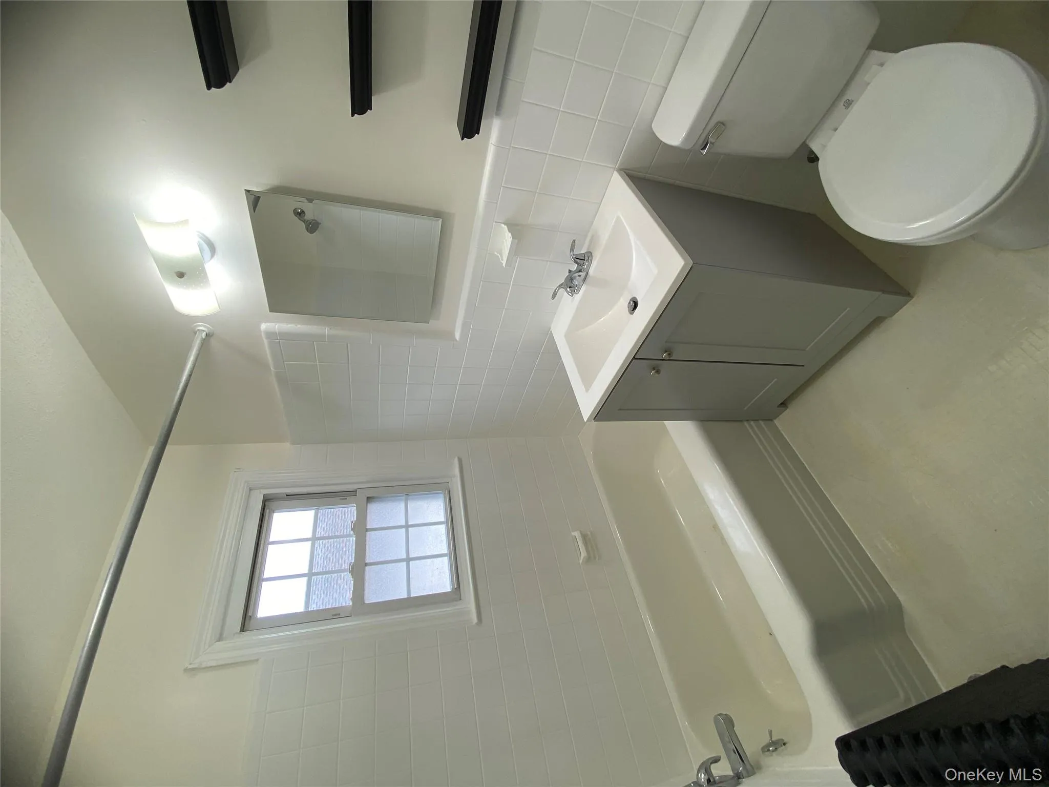 Bathroom with tile walls, vanity, washtub / shower combination, and wainscoting Bathroom with tile walls, vanity, washtub / shower combination, and wainscoting