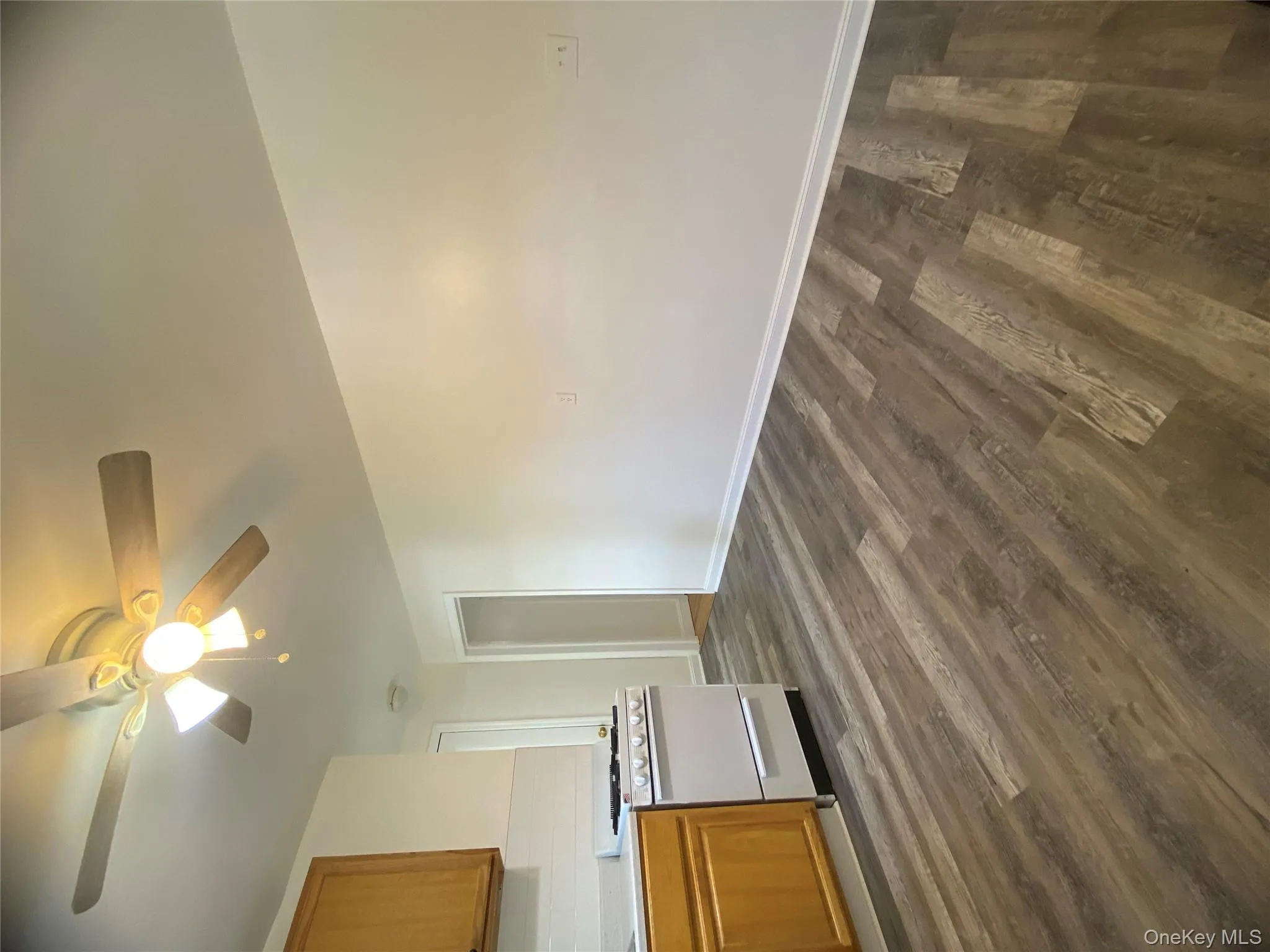 Kitchen with brown cabinetry, range, light countertops, and dark wood-type flooring Kitchen with brown cabinetry, range, light countertops, and dark wood-type flooring