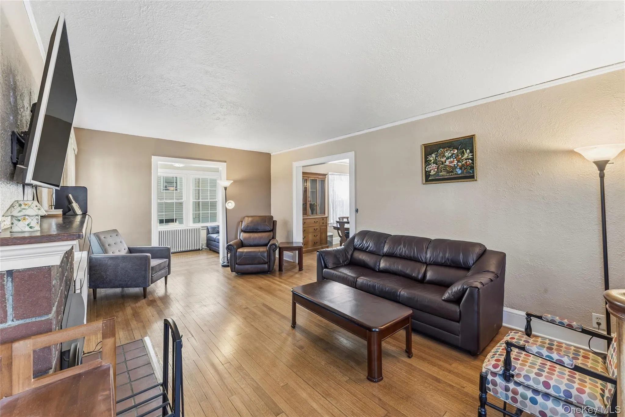 Living area featuring wood-type flooring, a textured wall, radiator, and a textured ceiling Living area featuring wood-type flooring, a textured wall, radiator, and a textured ceiling