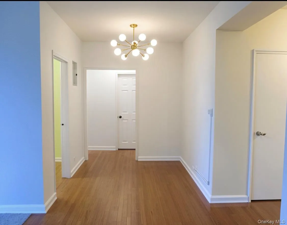Hallway featuring a chandelier and dark wood-style floors Hallway featuring a chandelier and dark wood-style floors