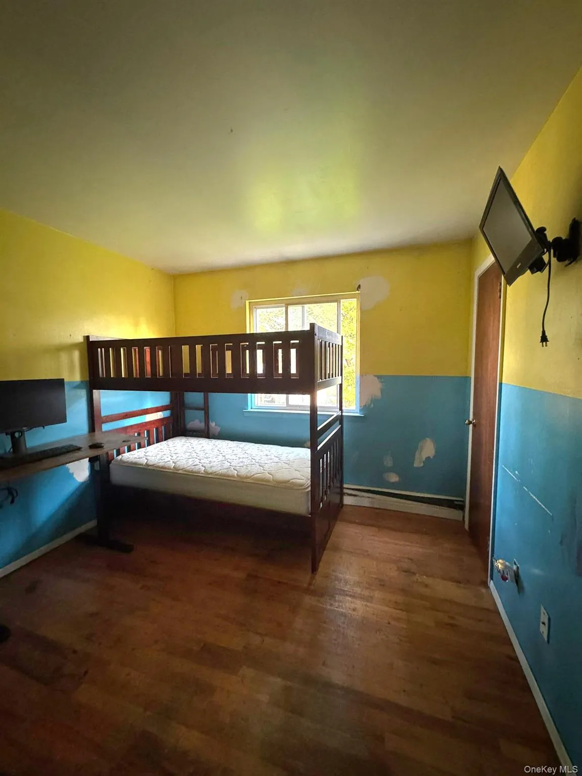 Bedroom with wood finished floors and a baseboard radiator Bedroom with wood finished floors and a baseboard radiator