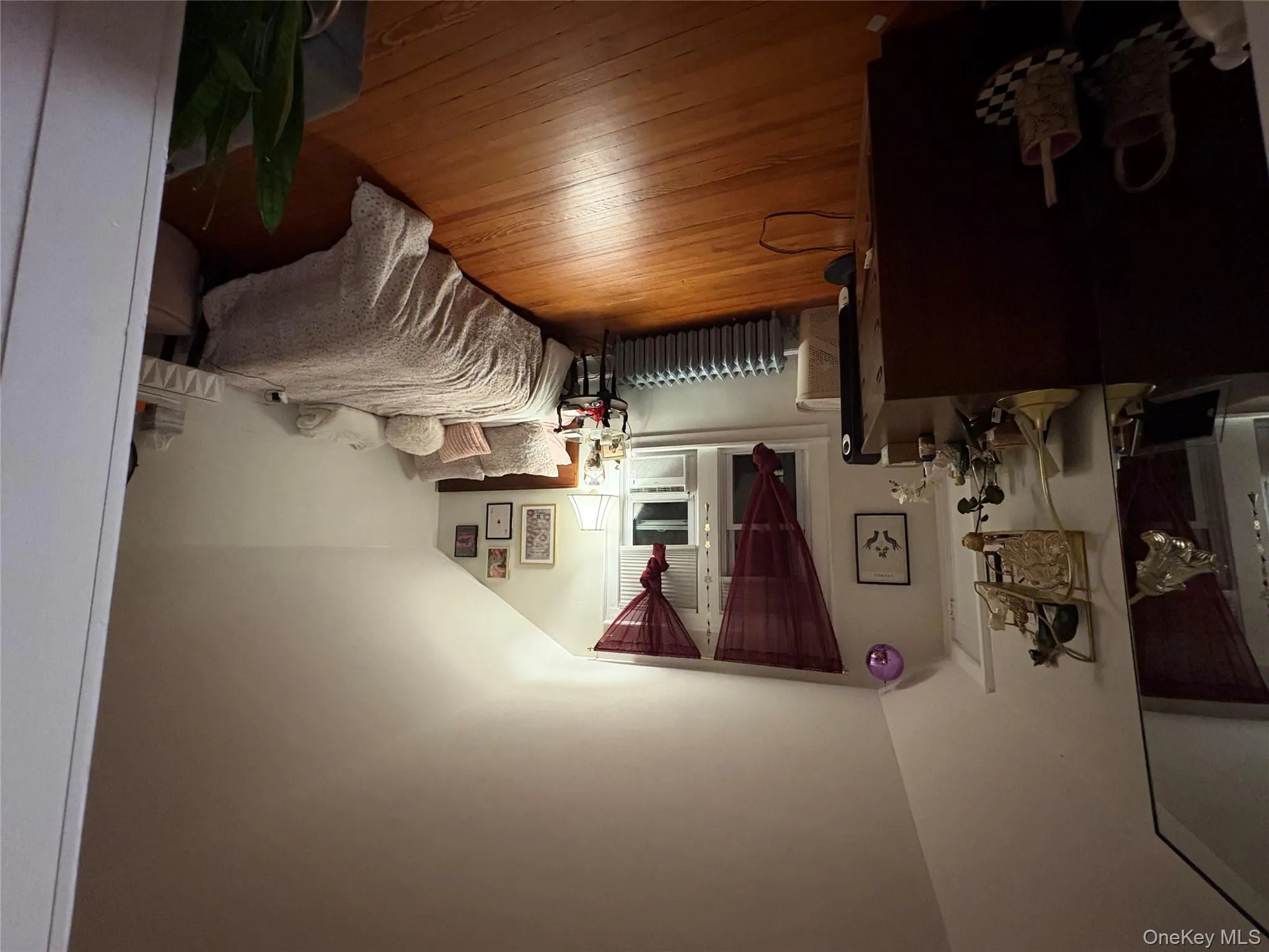 Bedroom featuring vaulted ceiling, light wood-style floors, and radiator heating unit Bedroom featuring vaulted ceiling, light wood-style floors, and radiator heating unit