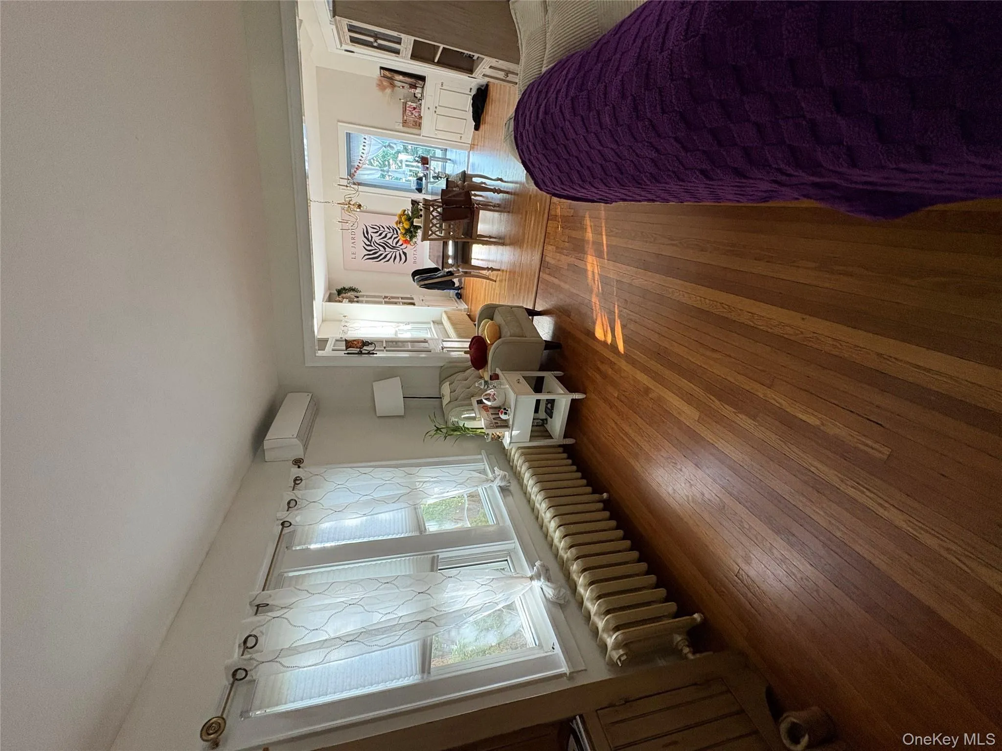 Living room featuring radiator heating unit, hardwood / wood-style flooring, a chandelier, and a wall unit AC Living room featuring radiator heating unit, hardwood / wood-style flooring, a chandelier, and a wall unit AC