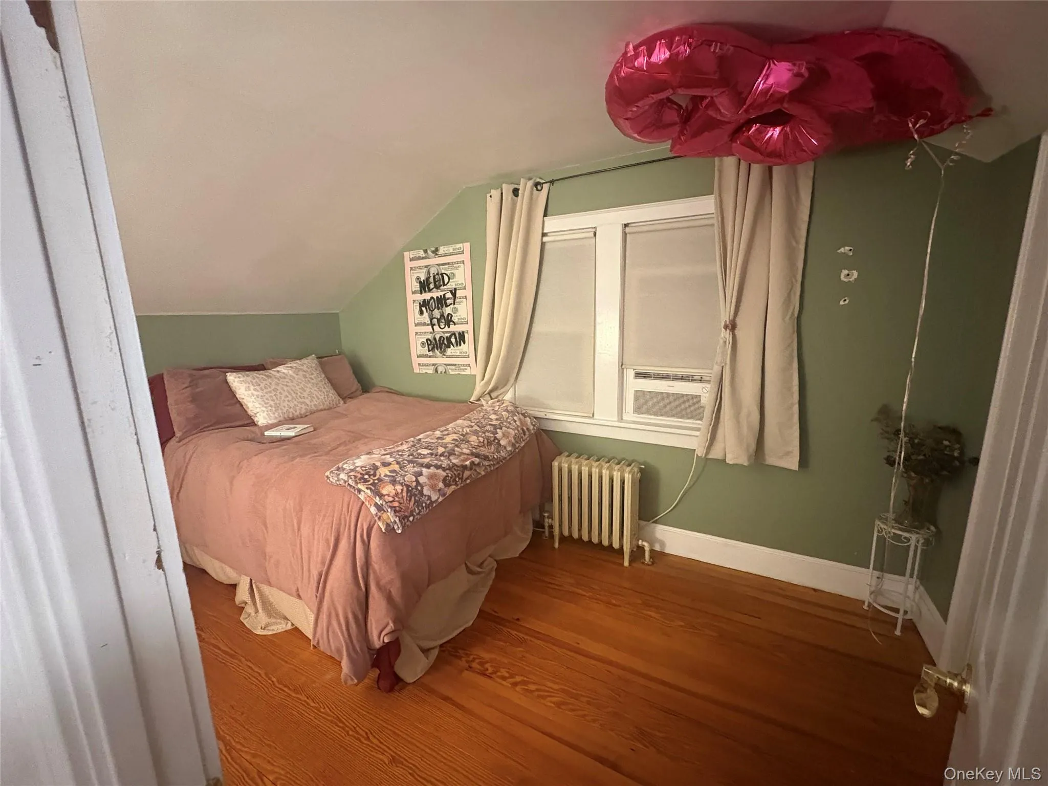 Bedroom featuring radiator heating unit, vaulted ceiling, wood finished floors, and cooling unit Bedroom featuring radiator heating unit, vaulted ceiling, wood finished floors, and cooling unit
