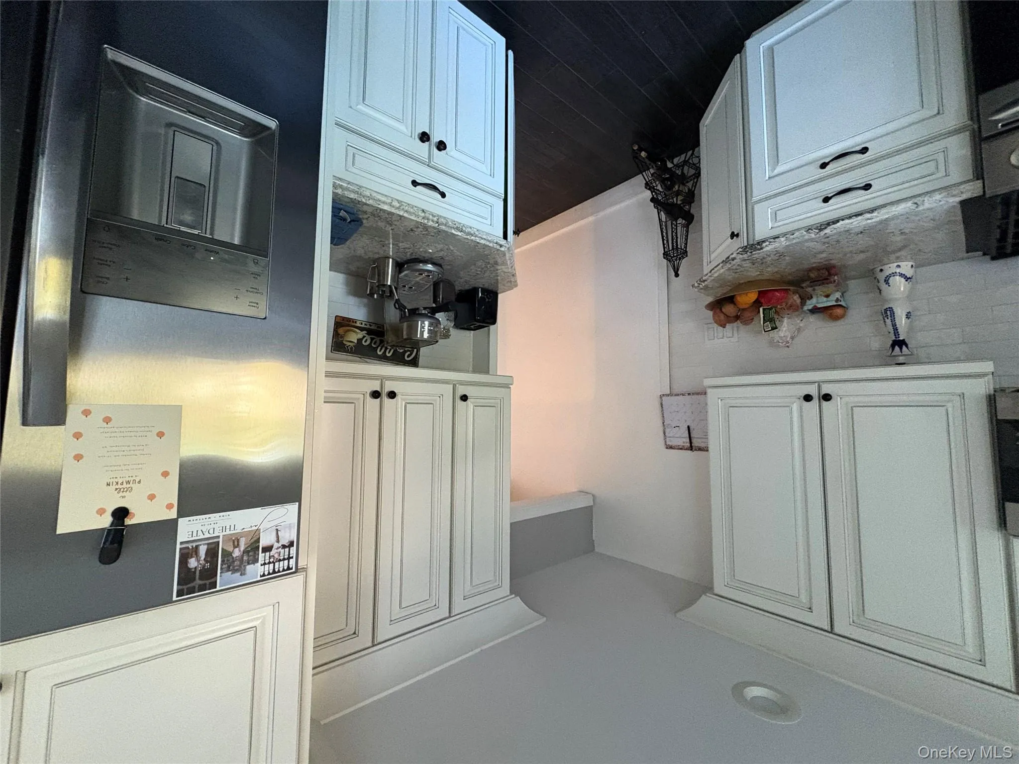 Kitchen featuring paneled refrigerator, light stone countertops, dark wood-type flooring, and white cabinets Kitchen featuring paneled refrigerator, light stone countertops, dark wood-type flooring, and white cabinets