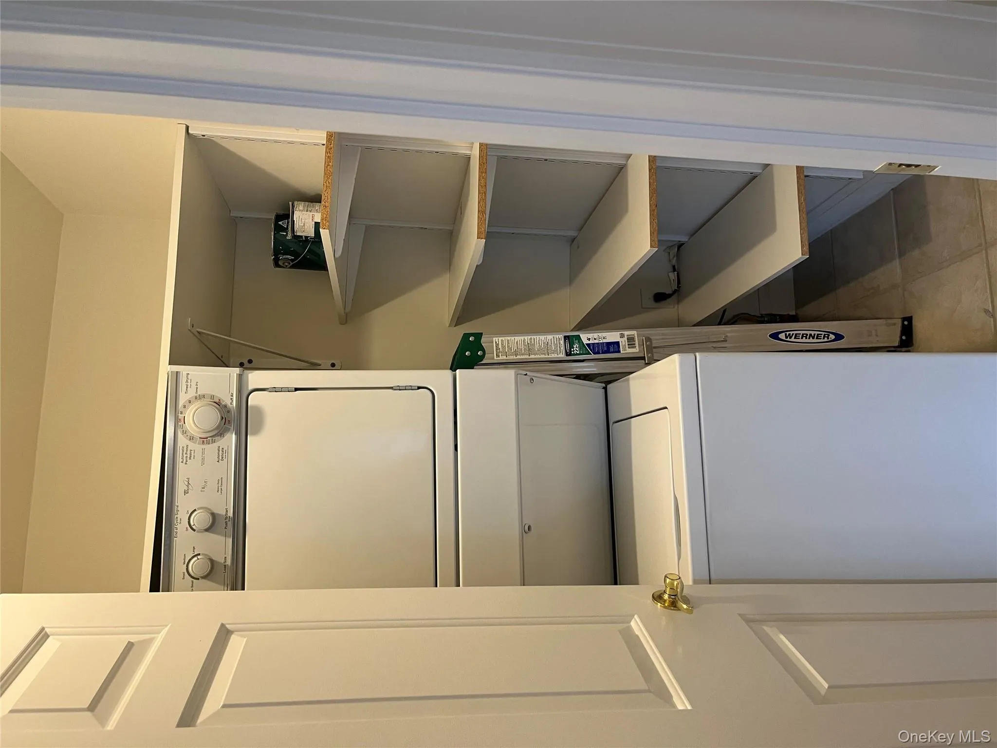 Washroom with stacked washer / dryer and light tile patterned floors Washroom with stacked washer / dryer and light tile patterned floors