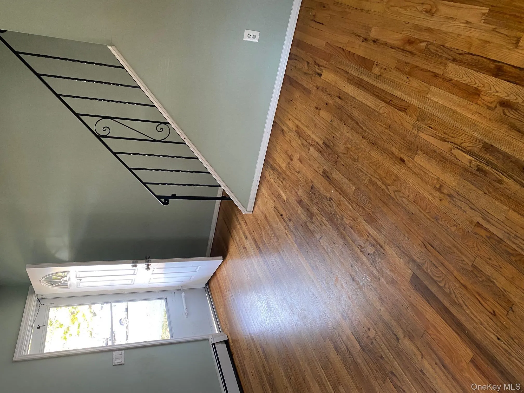 Foyer entrance with stairway, wood-type flooring, and a baseboard heating unit Foyer entrance with stairway, wood-type flooring, and a baseboard heating unit