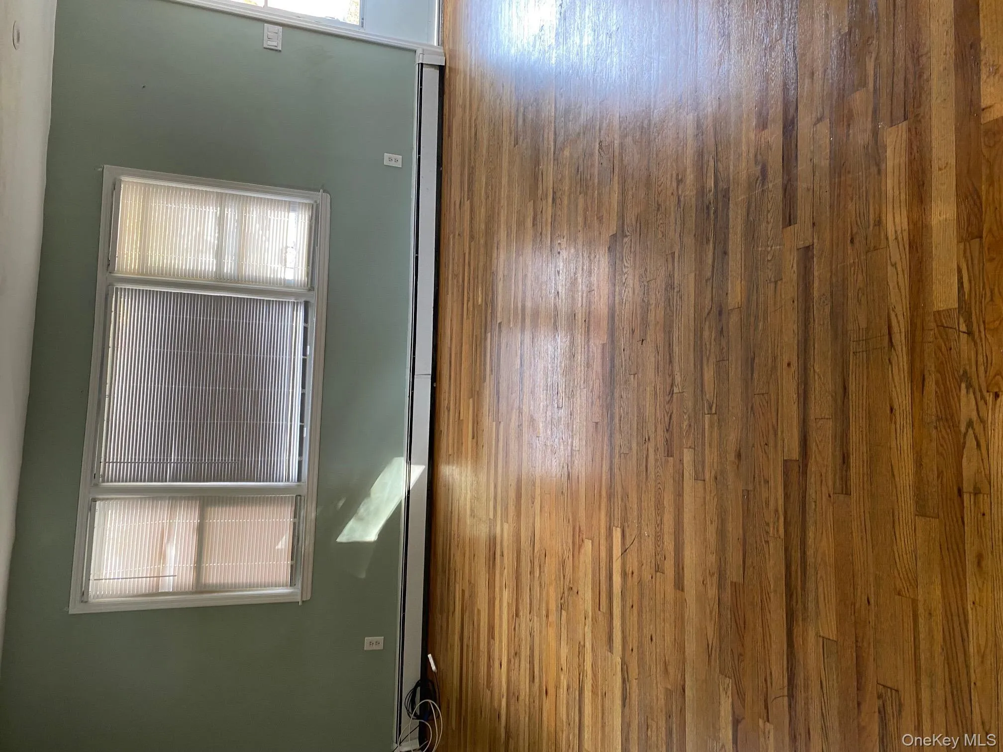 Empty room with healthy amount of natural light, a baseboard heating unit, and wood-type flooring Empty room with healthy amount of natural light, a baseboard heating unit, and wood-type flooring