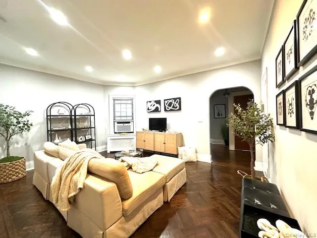 Living room featuring arched walkways, recessed lighting, and radiator Living room featuring arched walkways, recessed lighting, and radiator