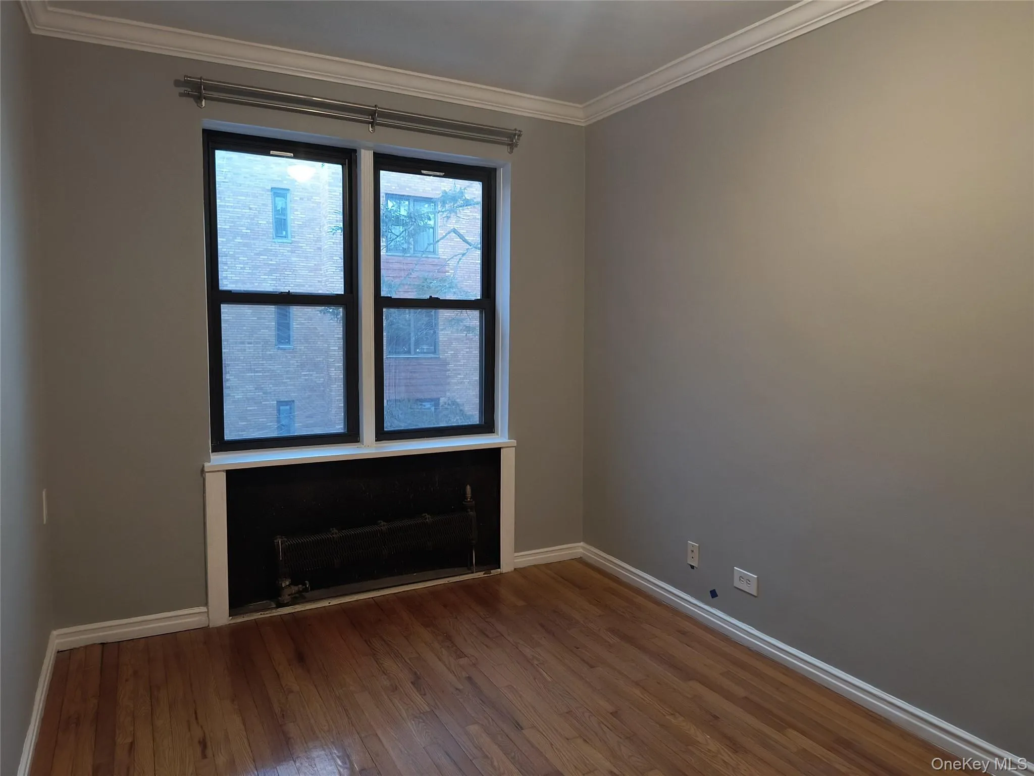 Empty room featuring ornamental molding and dark wood-style floors Empty room featuring ornamental molding and dark wood-style floors