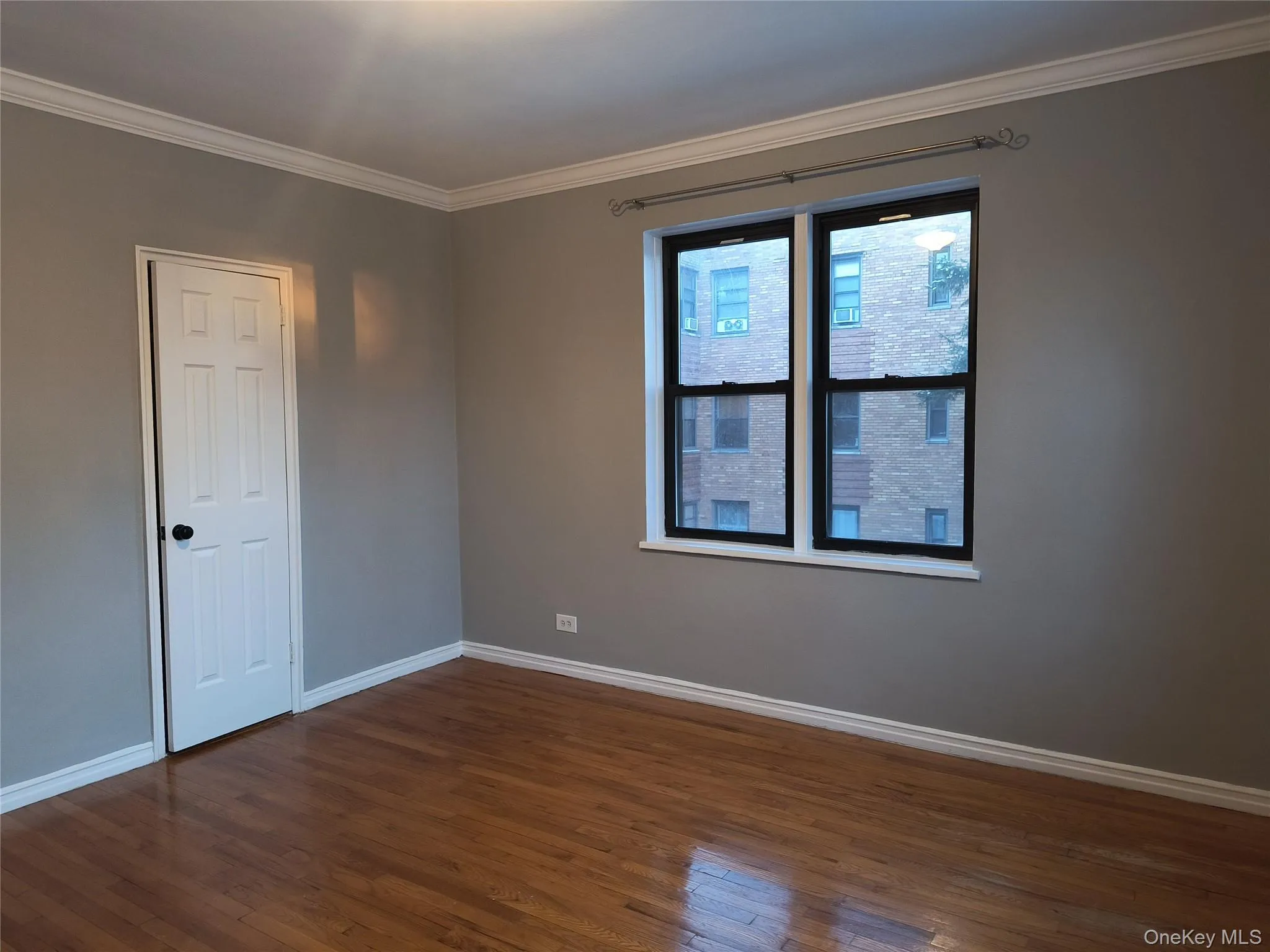 Empty room featuring crown molding and dark wood-style flooring Empty room featuring crown molding and dark wood-style flooring