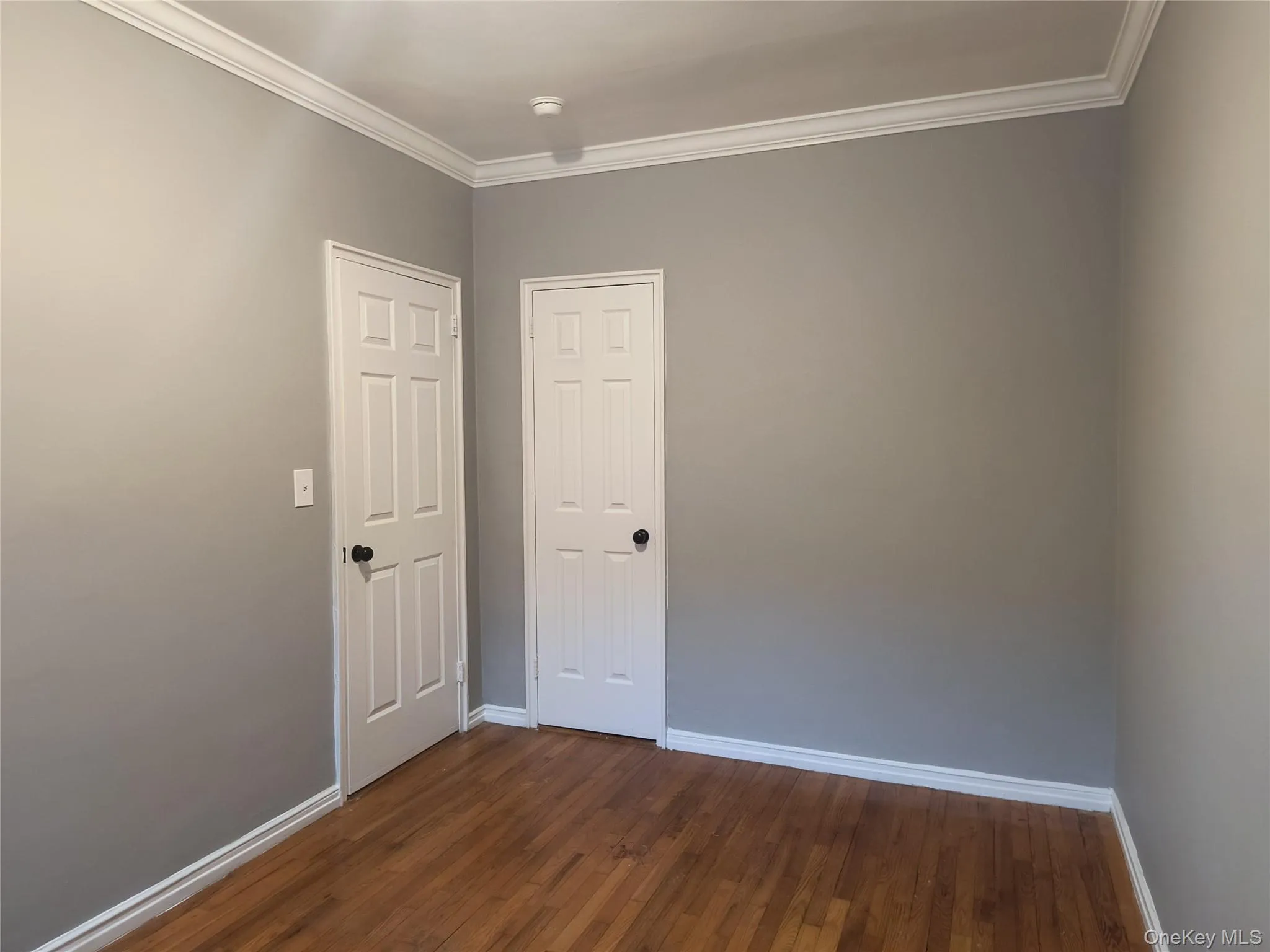 Spare room with crown molding and dark wood-type flooring Spare room with crown molding and dark wood-type flooring