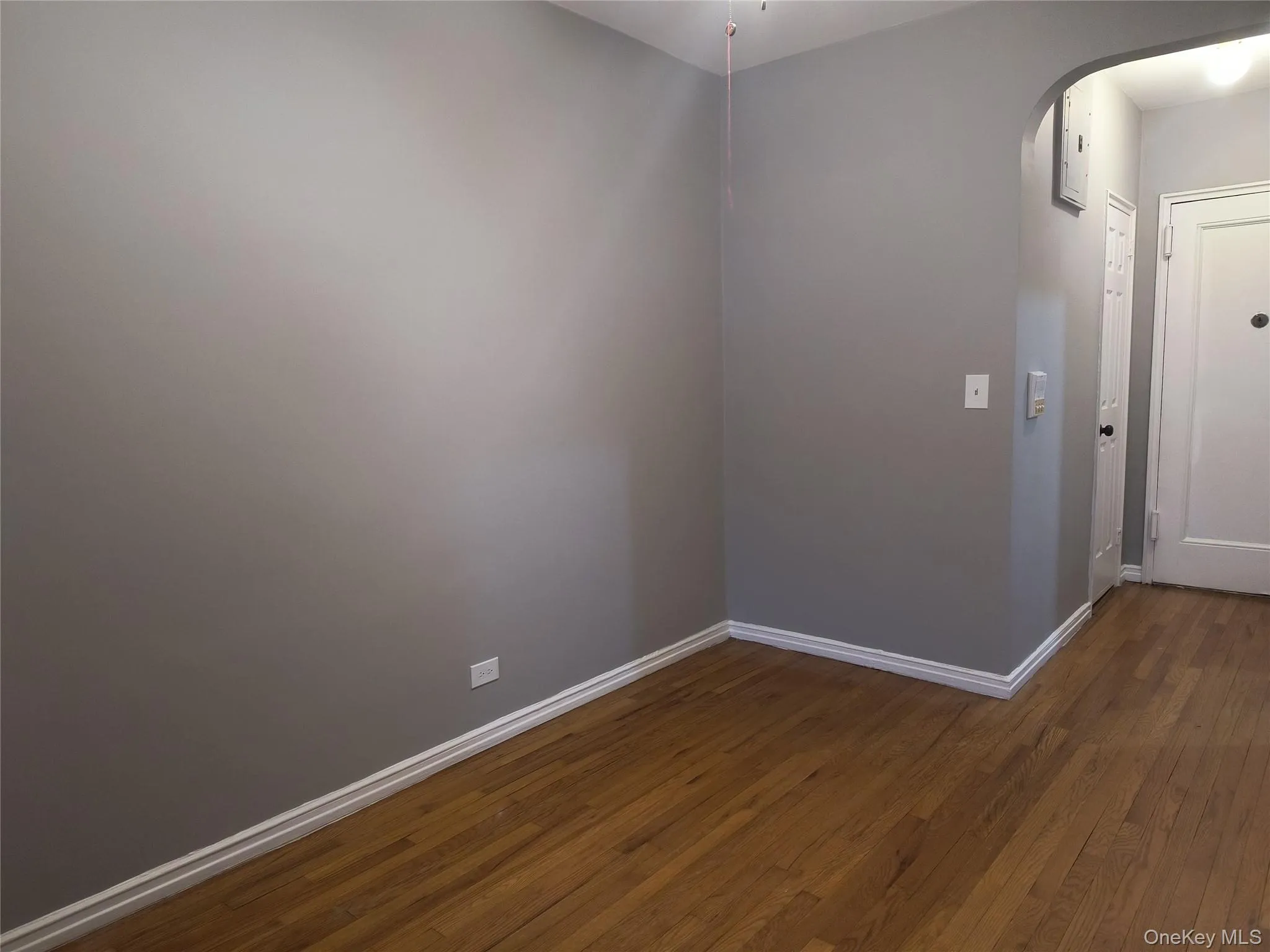 Spare room featuring dark wood-style floors and arched walkways Spare room featuring dark wood-style floors and arched walkways