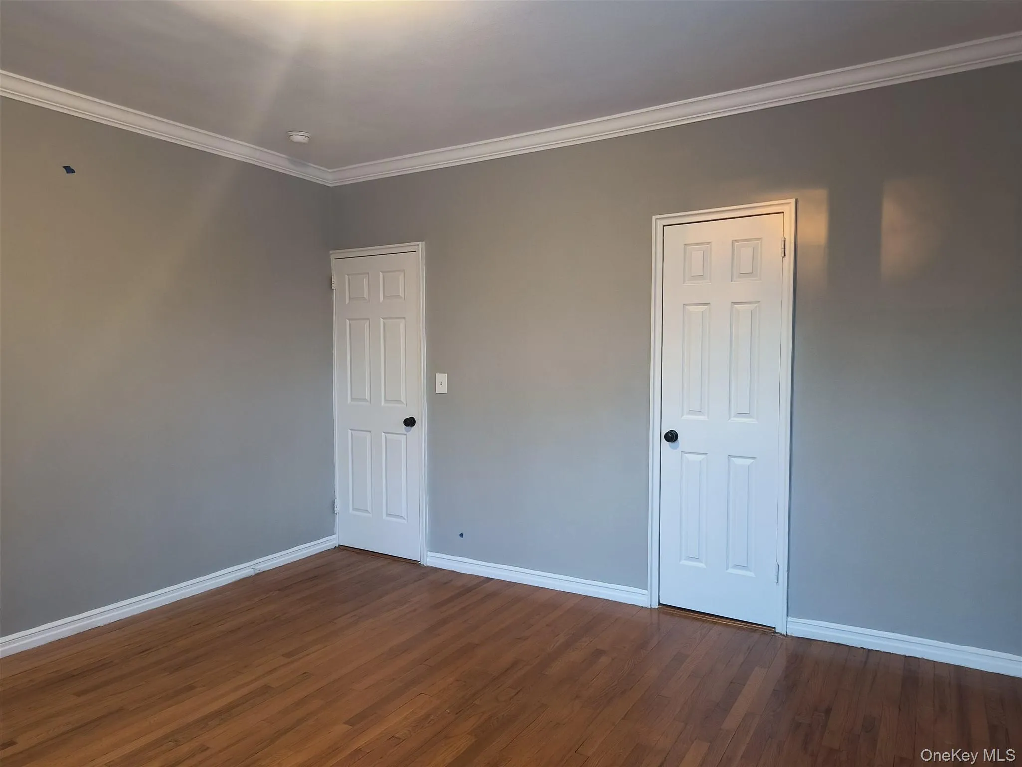 Empty room featuring ornamental molding and dark wood-type flooring Empty room featuring ornamental molding and dark wood-type flooring