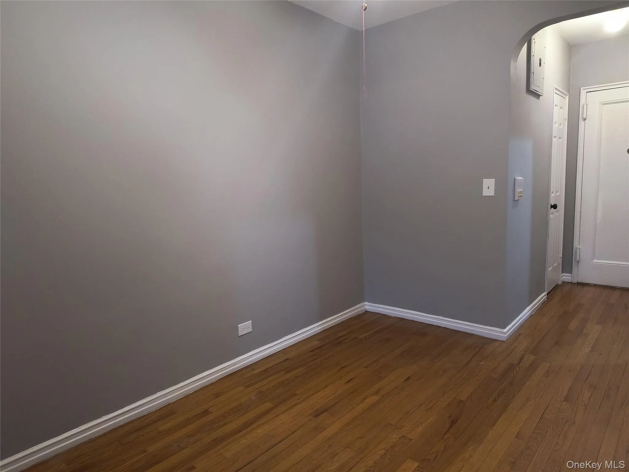 Empty room with dark wood-style flooring and arched walkways Empty room with dark wood-style flooring and arched walkways