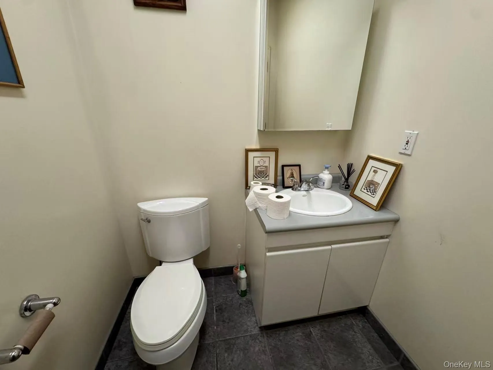 Half bathroom with vanity and dark tile patterned flooring Half bathroom with vanity and dark tile patterned flooring