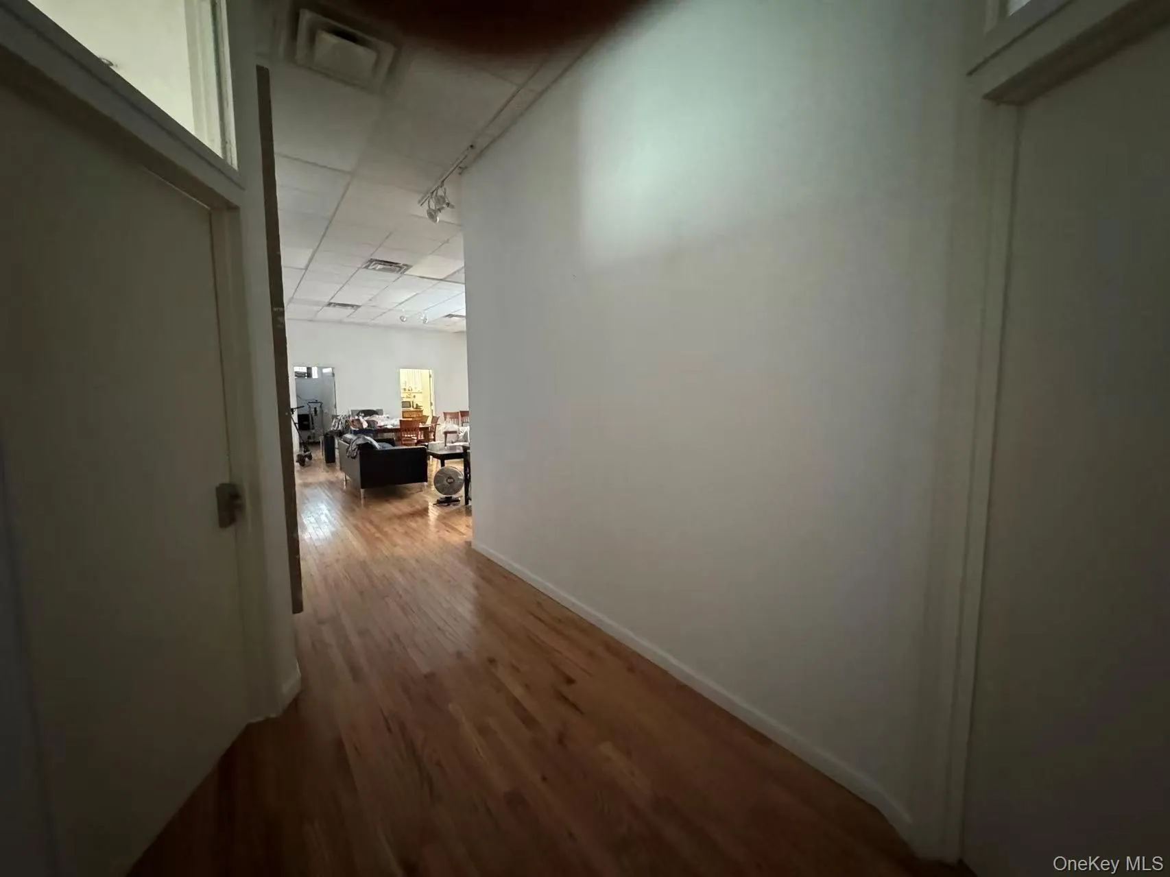 Hallway featuring dark wood-style flooring and track lighting Hallway featuring dark wood-style flooring and track lighting