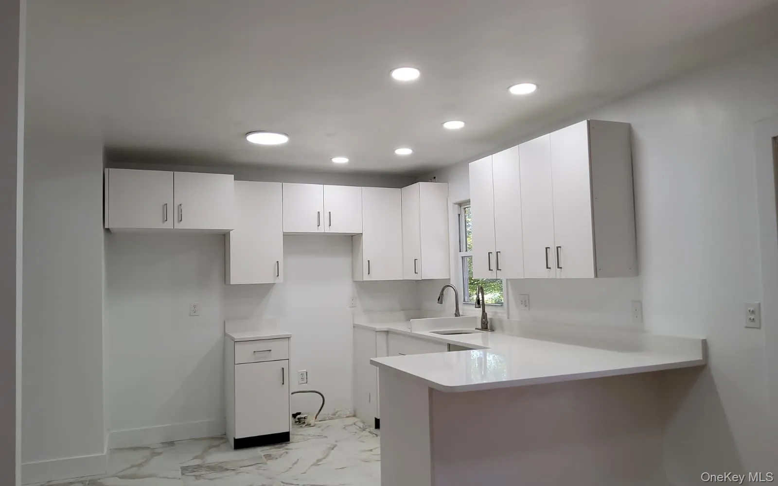 Kitchen featuring light marble finish floors, a peninsula, white cabinets, recessed lighting, and light stone countertops Kitchen featuring light marble finish floors, a peninsula, white cabinets, recessed lighting, and light stone countertops