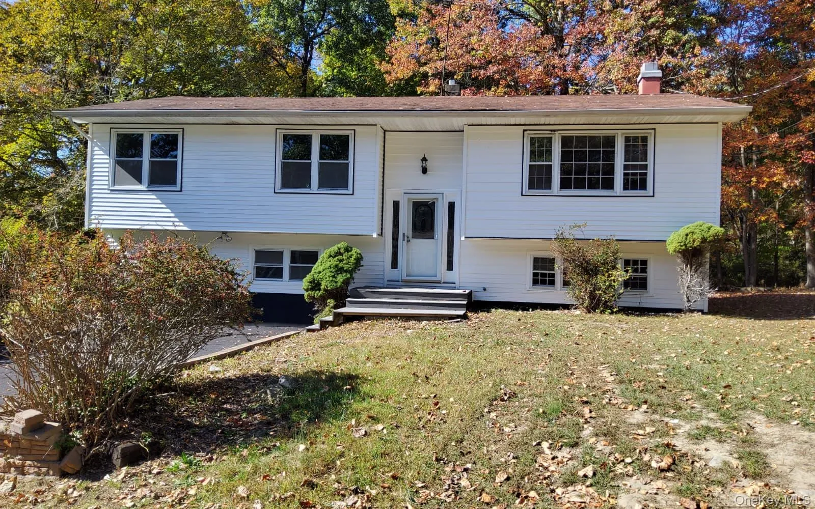 Split foyer home with a chimney and a front yard Split foyer home with a chimney and a front yard