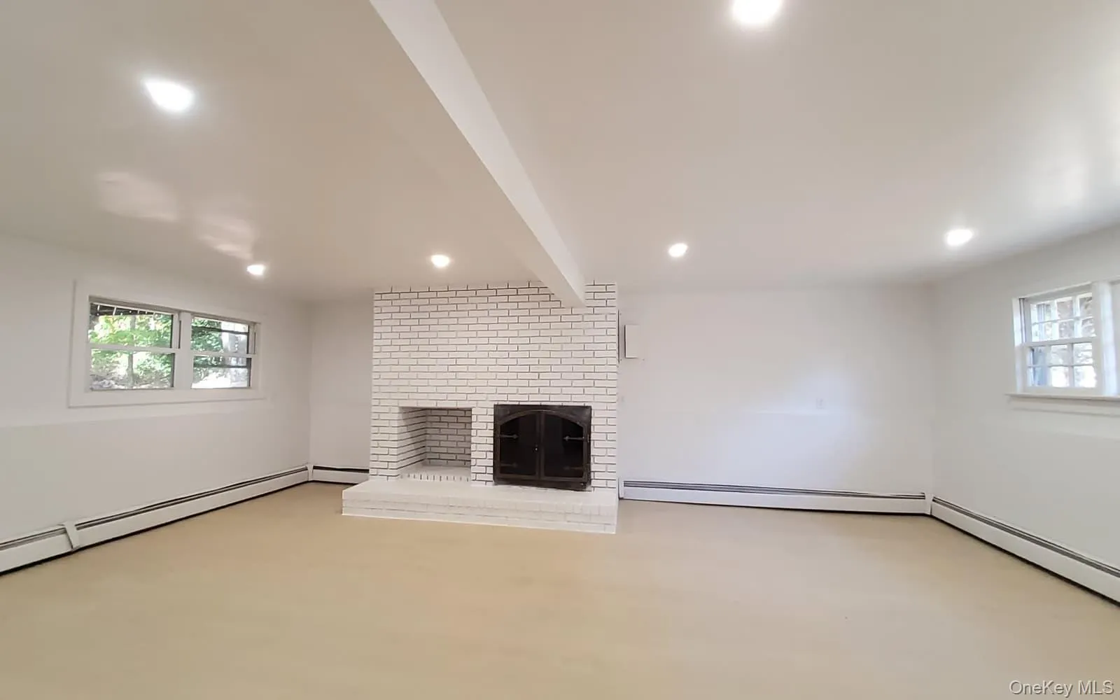 Unfurnished living room featuring a brick fireplace, a baseboard radiator, beamed ceiling, and recessed lighting Unfurnished living room featuring a brick fireplace, a baseboard radiator, beamed ceiling, and recessed lighting