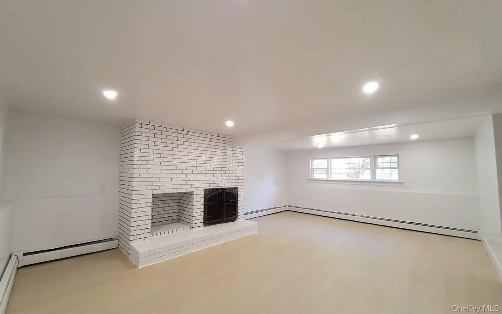 Unfurnished living room featuring a brick fireplace, recessed lighting, and a baseboard heating unit Unfurnished living room featuring a brick fireplace, recessed lighting, and a baseboard heating unit