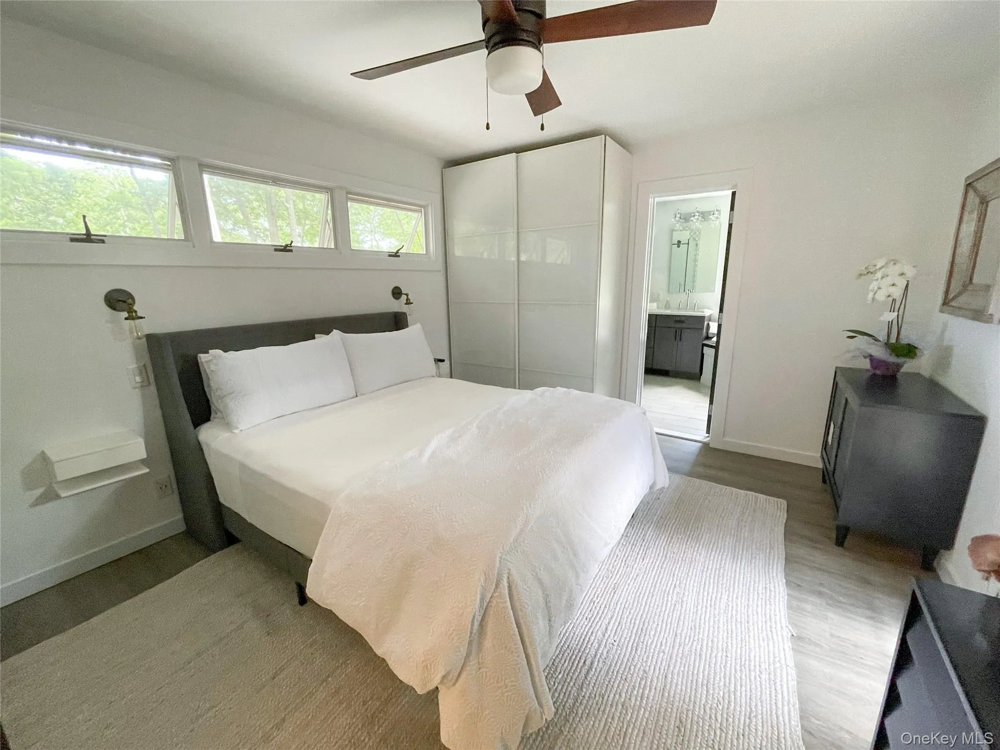 Bedroom featuring multiple windows, hardwood / wood-style floors, ensuite bath, and ceiling fan Bedroom featuring multiple windows, hardwood / wood-style floors, ensuite bath, and ceiling fan