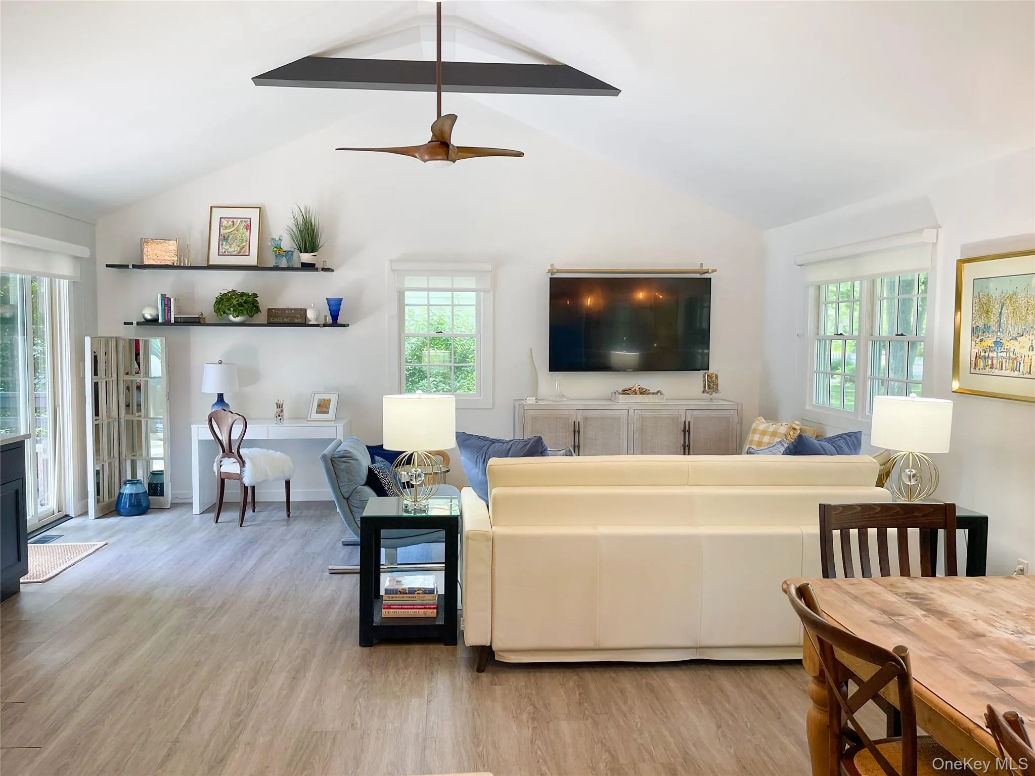 Living room with lofted ceiling with beams, ceiling fan, a wood stove, and light hardwood / wood-style flooring Living room with lofted ceiling with beams, ceiling fan, a wood stove, and light hardwood / wood-style flooring