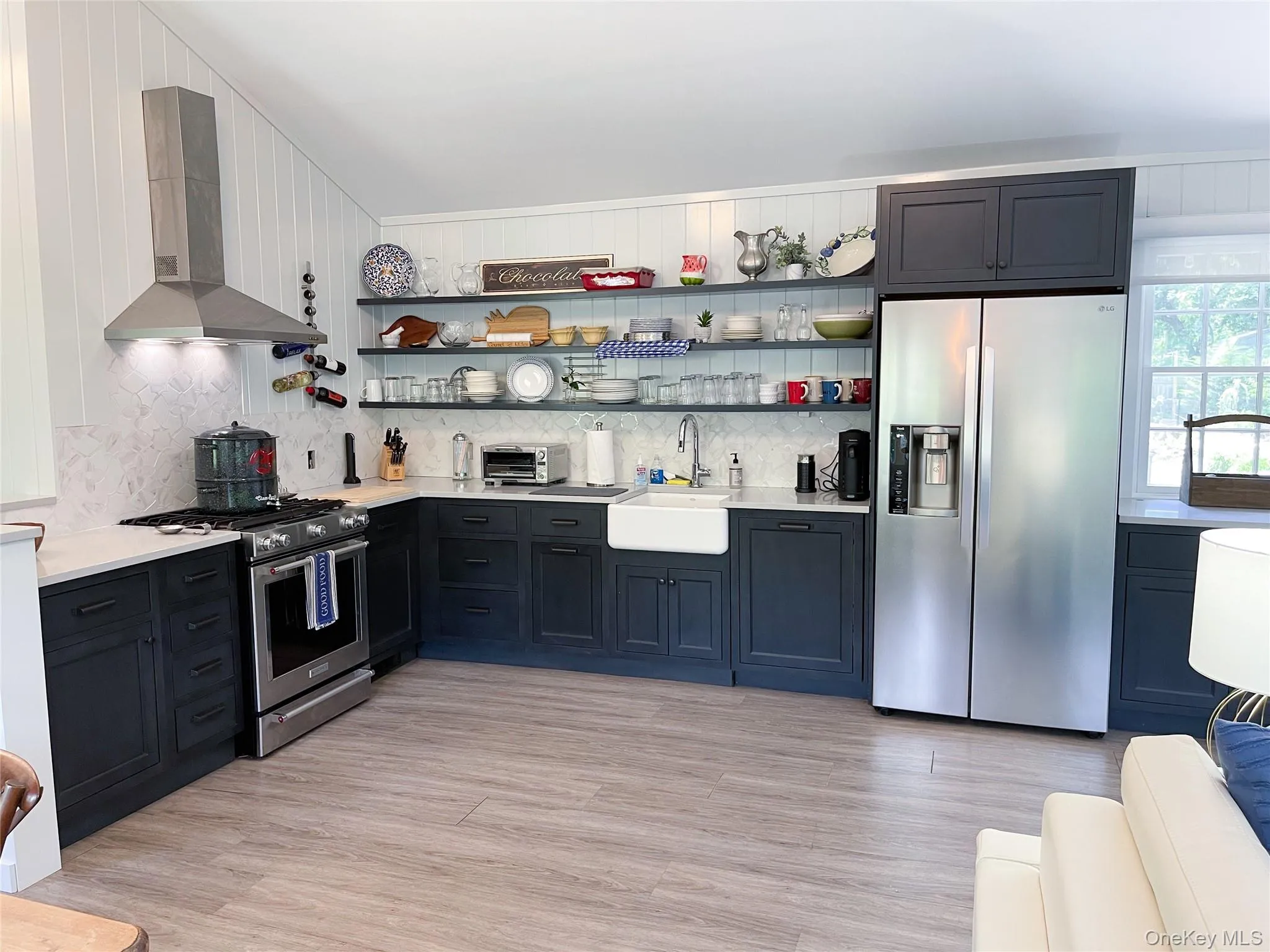 Kitchen featuring appliances with stainless steel finishes, wall chimney range hood, open shelves, and tasteful backsplash Kitchen featuring appliances with stainless steel finishes, wall chimney range hood, open shelves, and tasteful backsplash