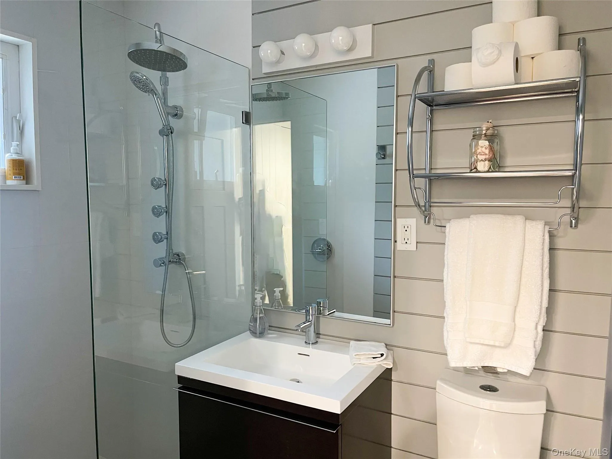 Bathroom with tiled shower, vanity, toilet, and wood walls Bathroom with tiled shower, vanity, toilet, and wood walls