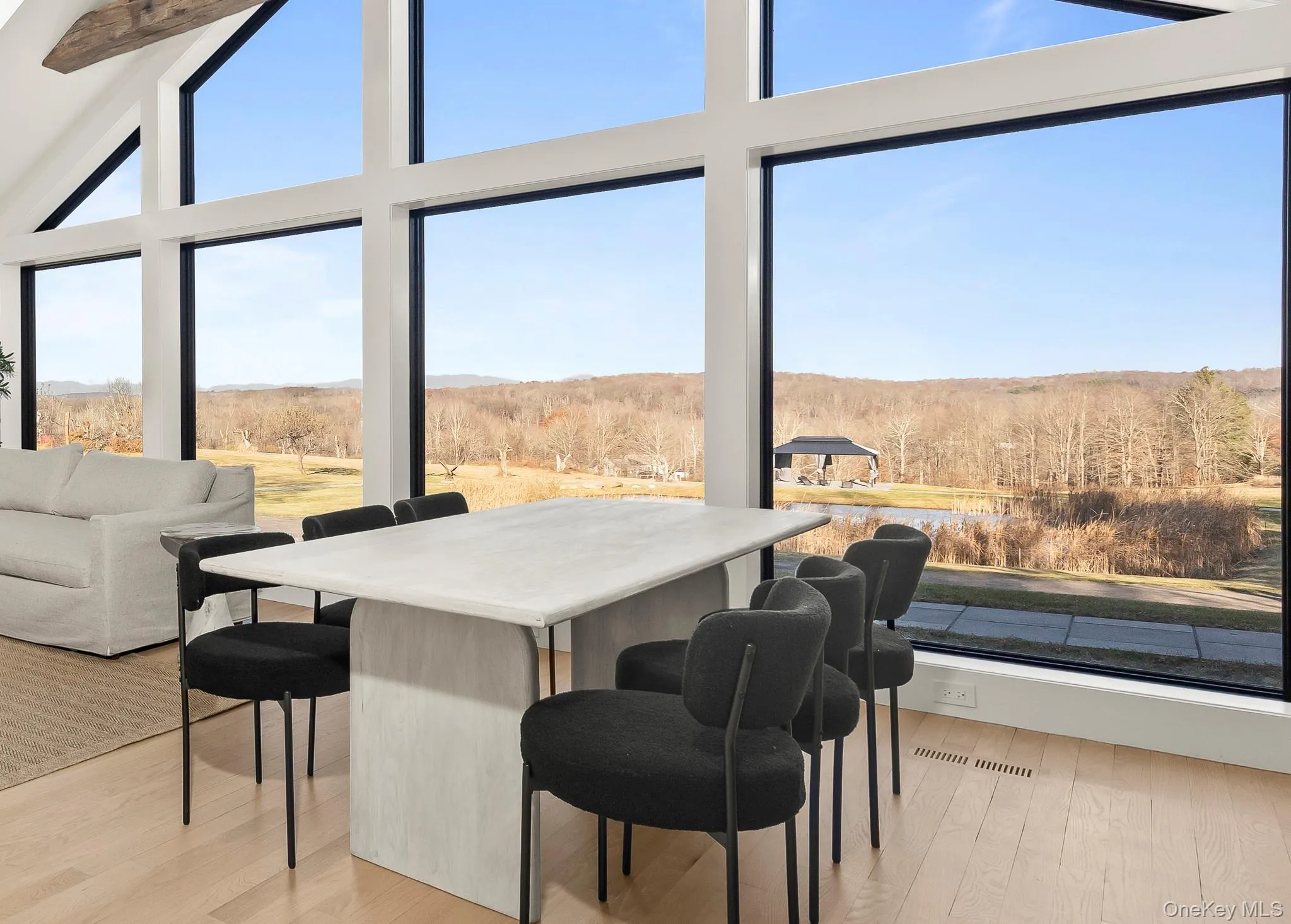 Dining area featuring wood flooring, a view of land, and high vaulted ceiling Dining area featuring wood flooring, a view of land, and high vaulted ceiling