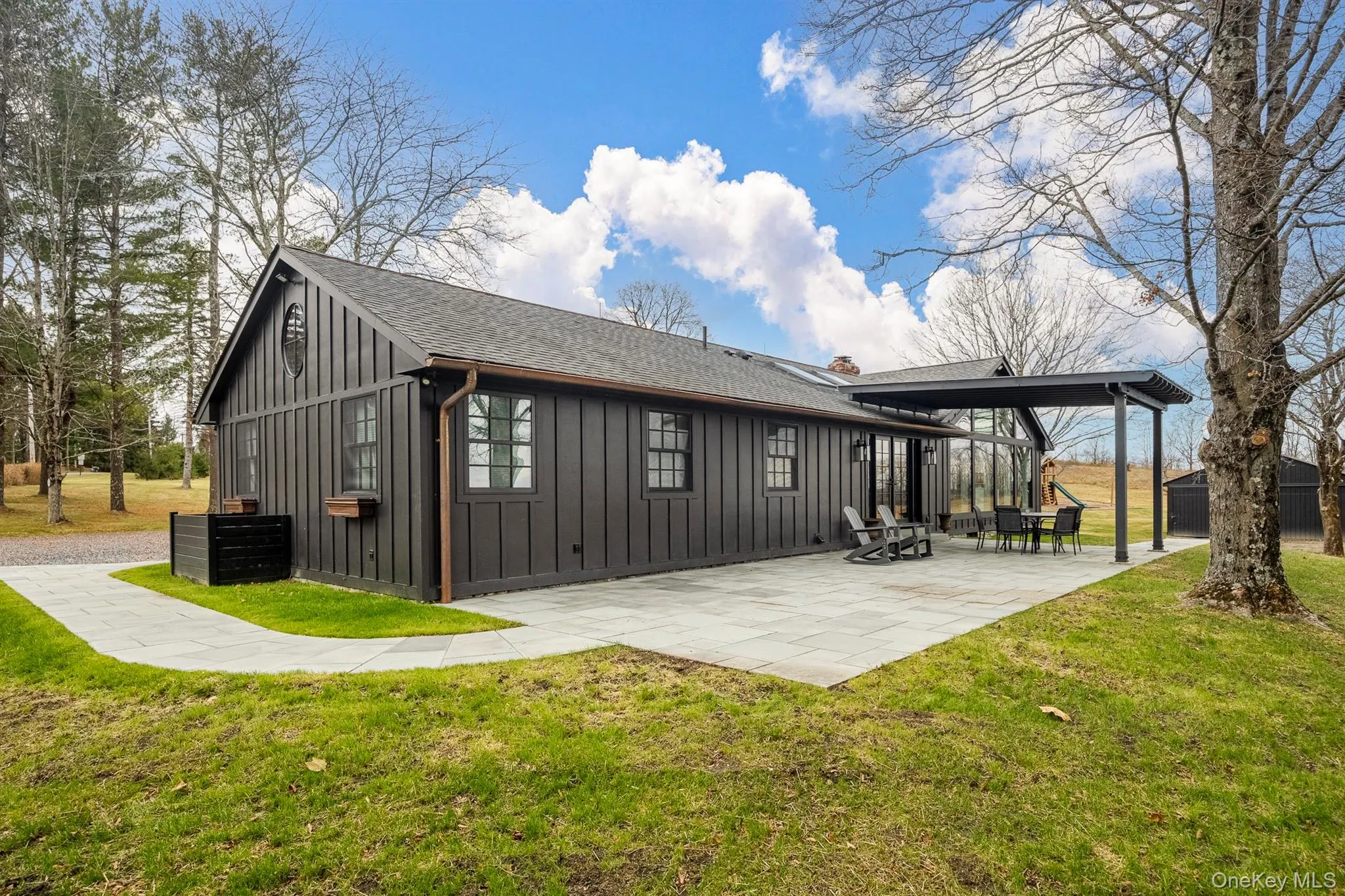 Back of property featuring board and batten siding, a lawn, and a patio Back of property featuring board and batten siding, a lawn, and a patio