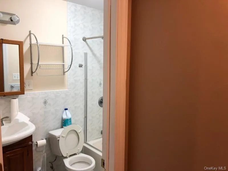 Full bath featuring vanity, shower / bathtub combination, and tile walls Full bath featuring vanity, shower / bathtub combination, and tile walls